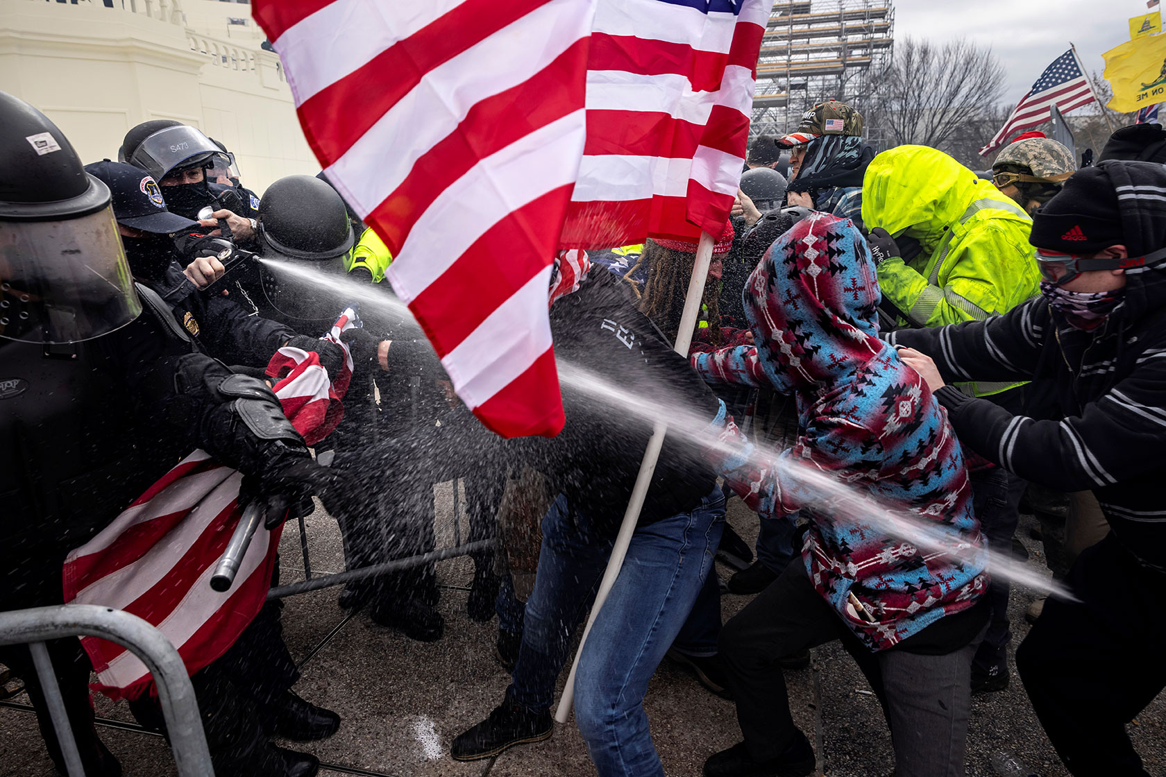 Photo shows police spraying rioters holding large American flags