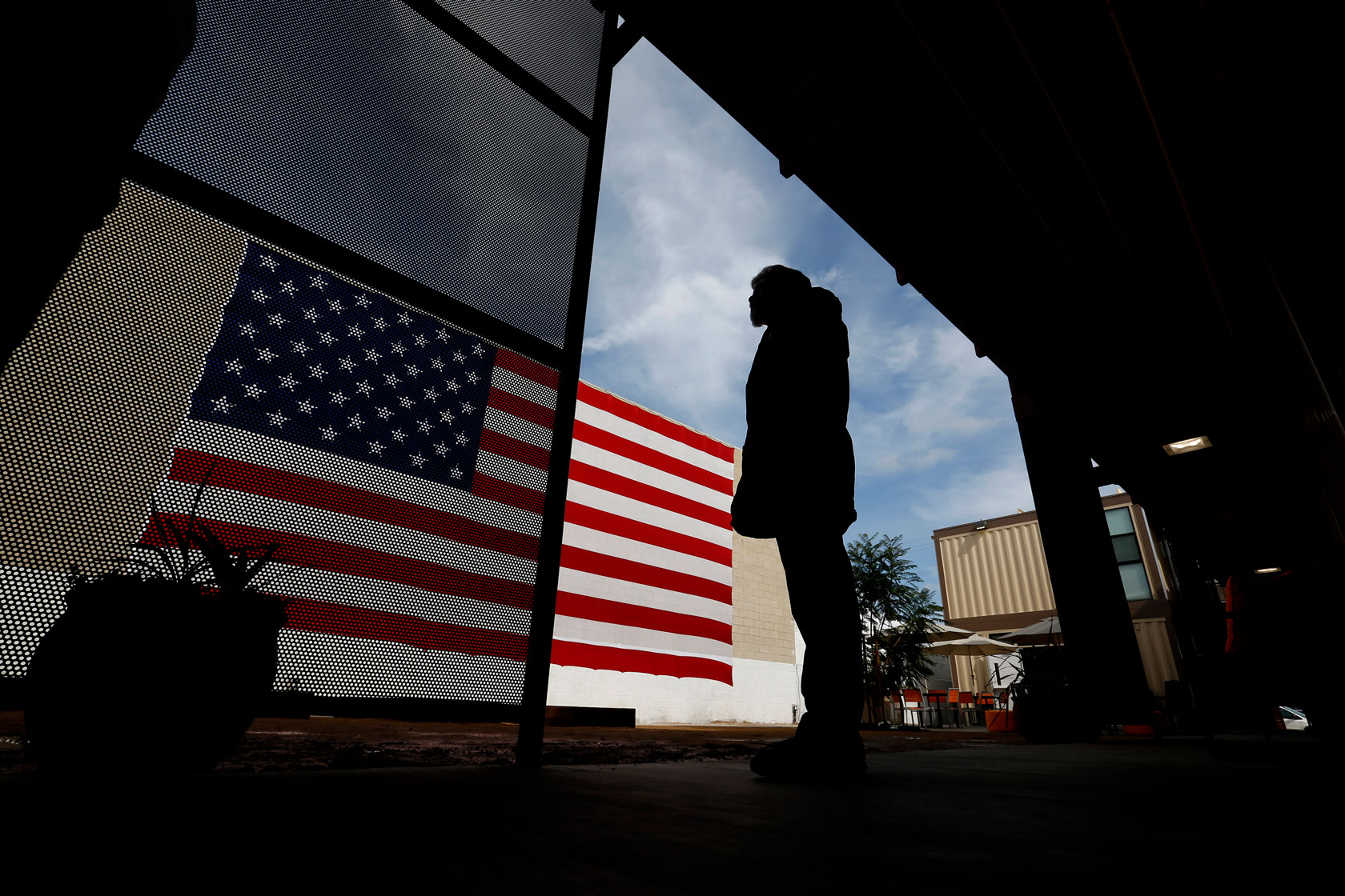 A person looks out over a courtyard that has an American flag painted on a wall.