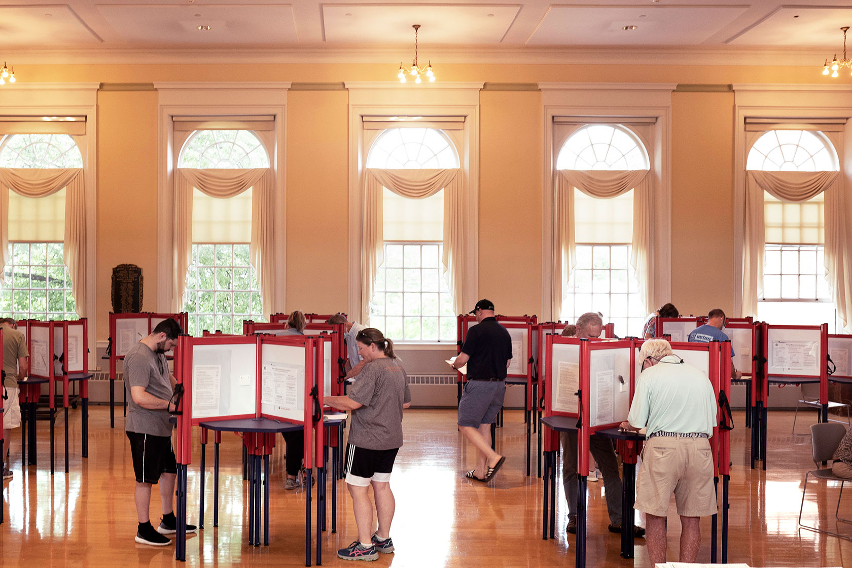 Voters casting ballots in room with high windows