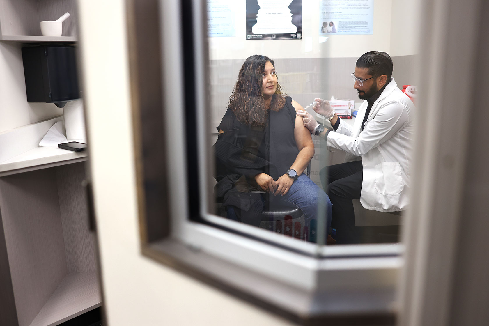 A patient receives a COVID-19 vaccine from a pharmacist at CVS.