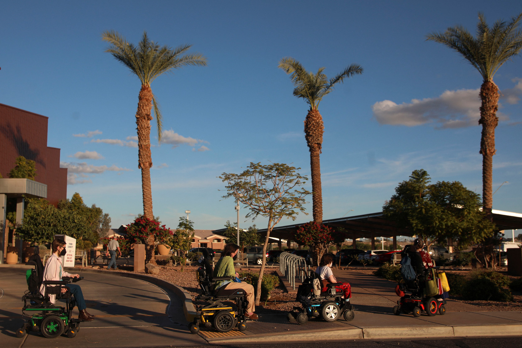 A group of people on motorized wheelchairs ride down a sidewalk in Yuma, Arizona.