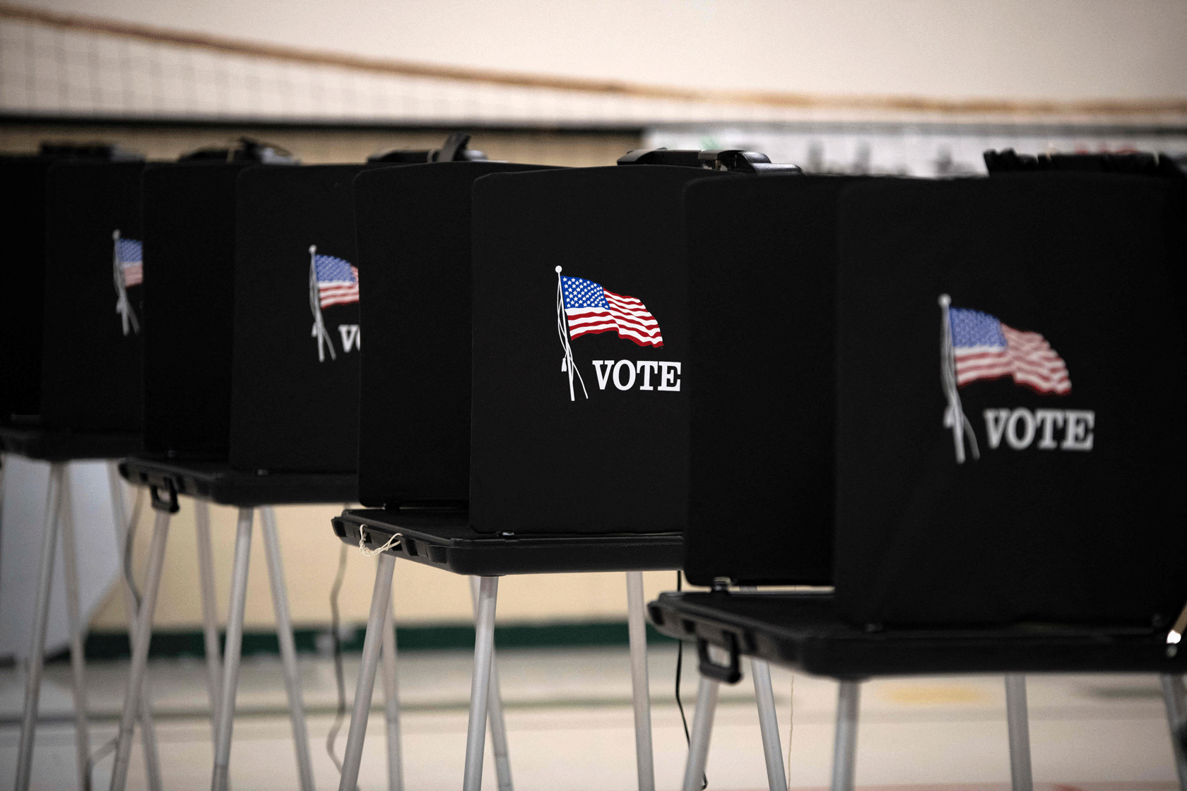Black voting booths with American flags on them are seen in a row.