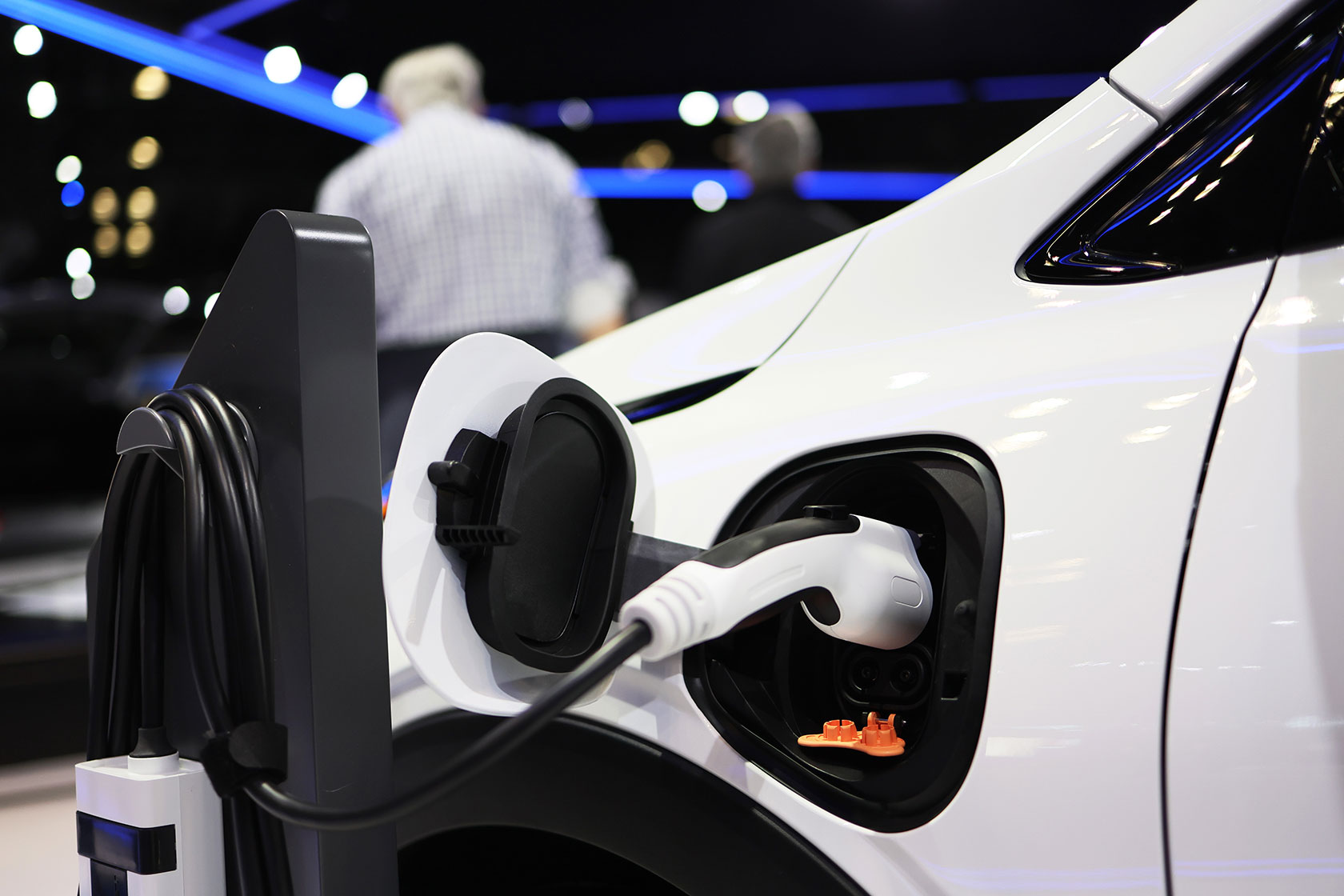 Photo shows an up-close image of a white car with a charger attached to it