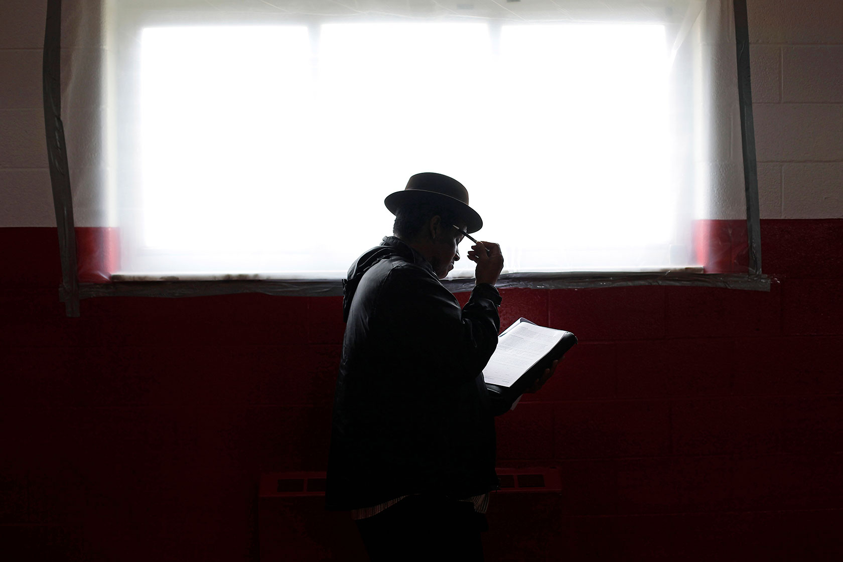 Person stands at window filling out paper application.