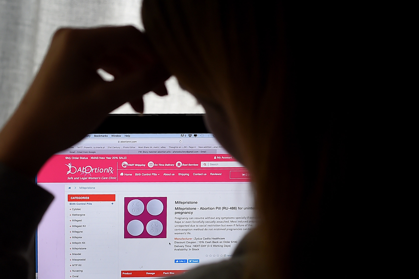 A woman seeking an abortion looks at a computer where a webpage for abortion pills is visible.