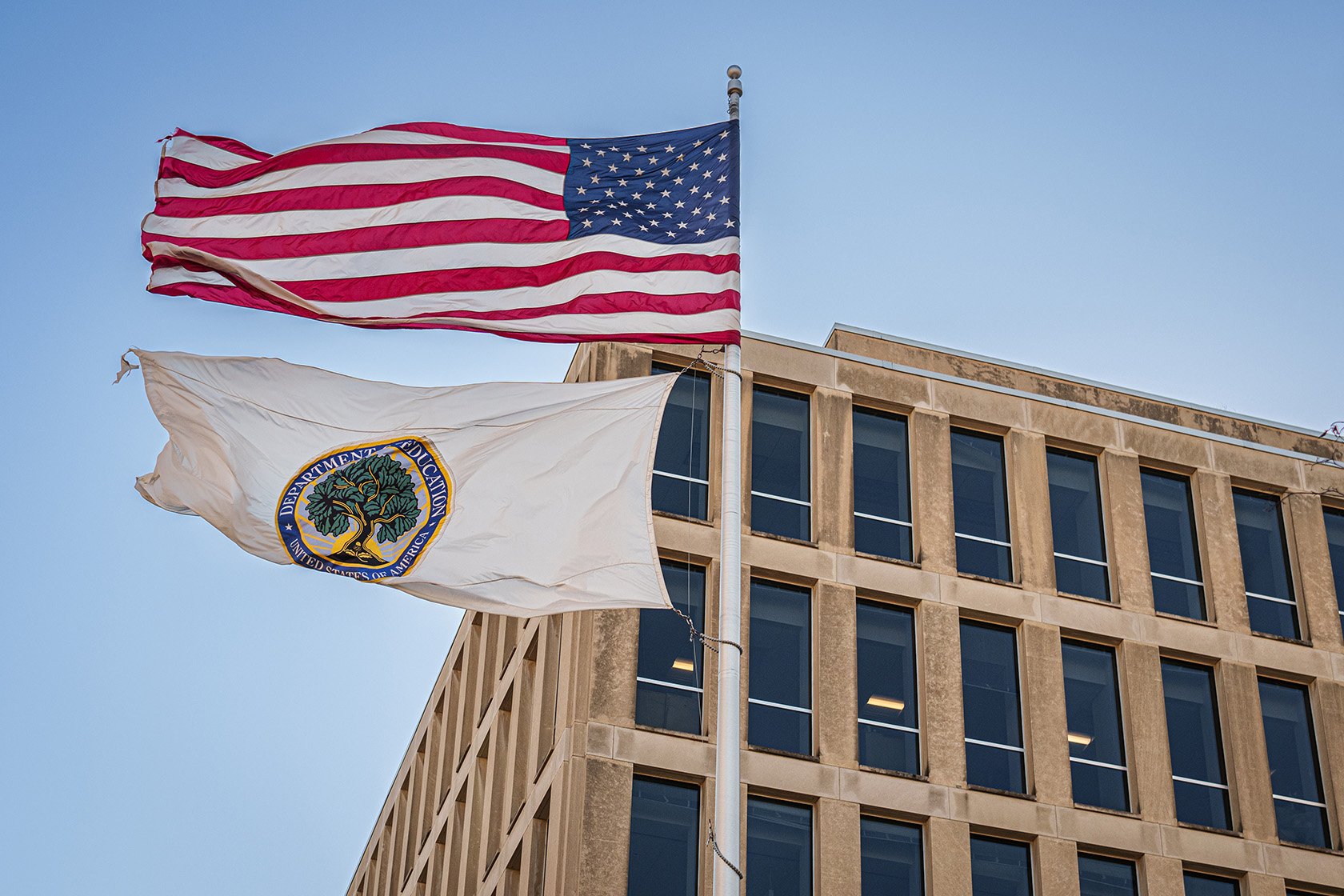 The American flag and the Department of Education flag fly above the U.S. Department of Education headquarters.
