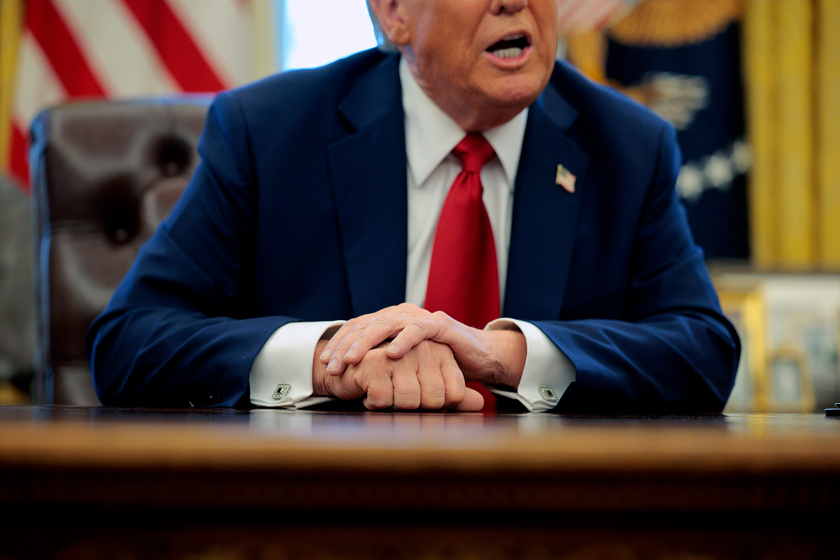 U.S. President Donald Trump talks to reporters from the Resolute Desk of the Oval Office after signing an executive order.