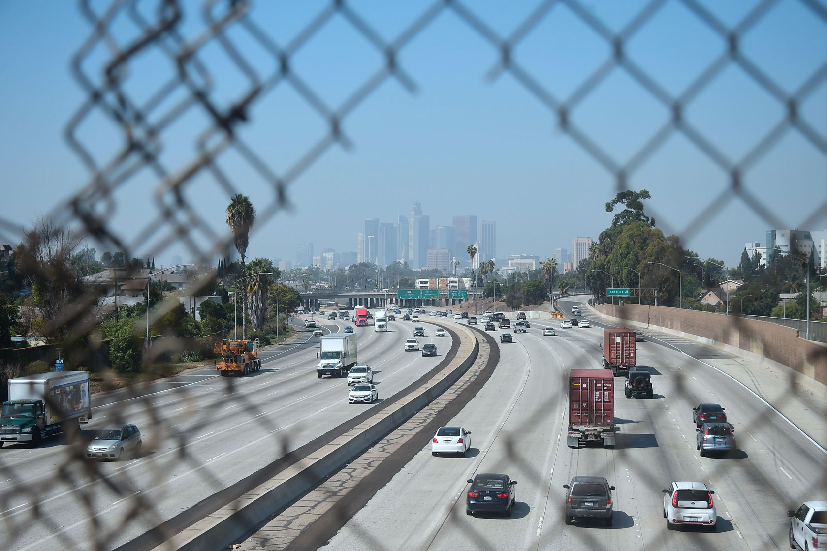 Cars travel on the highway to and from Los Angeles, which is enveloped in smog.