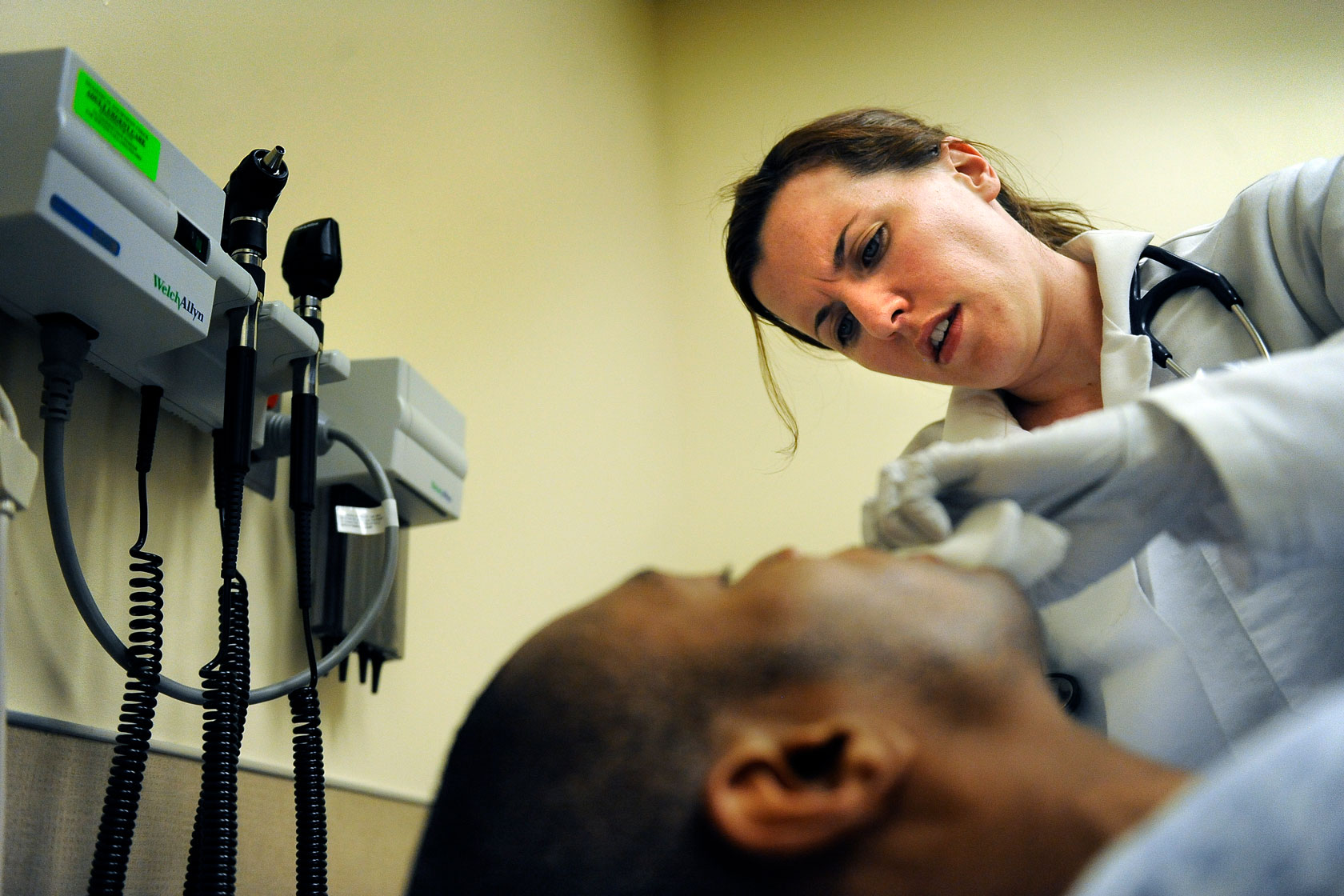 A patient lies on a table as a nurse practitioner examines him.