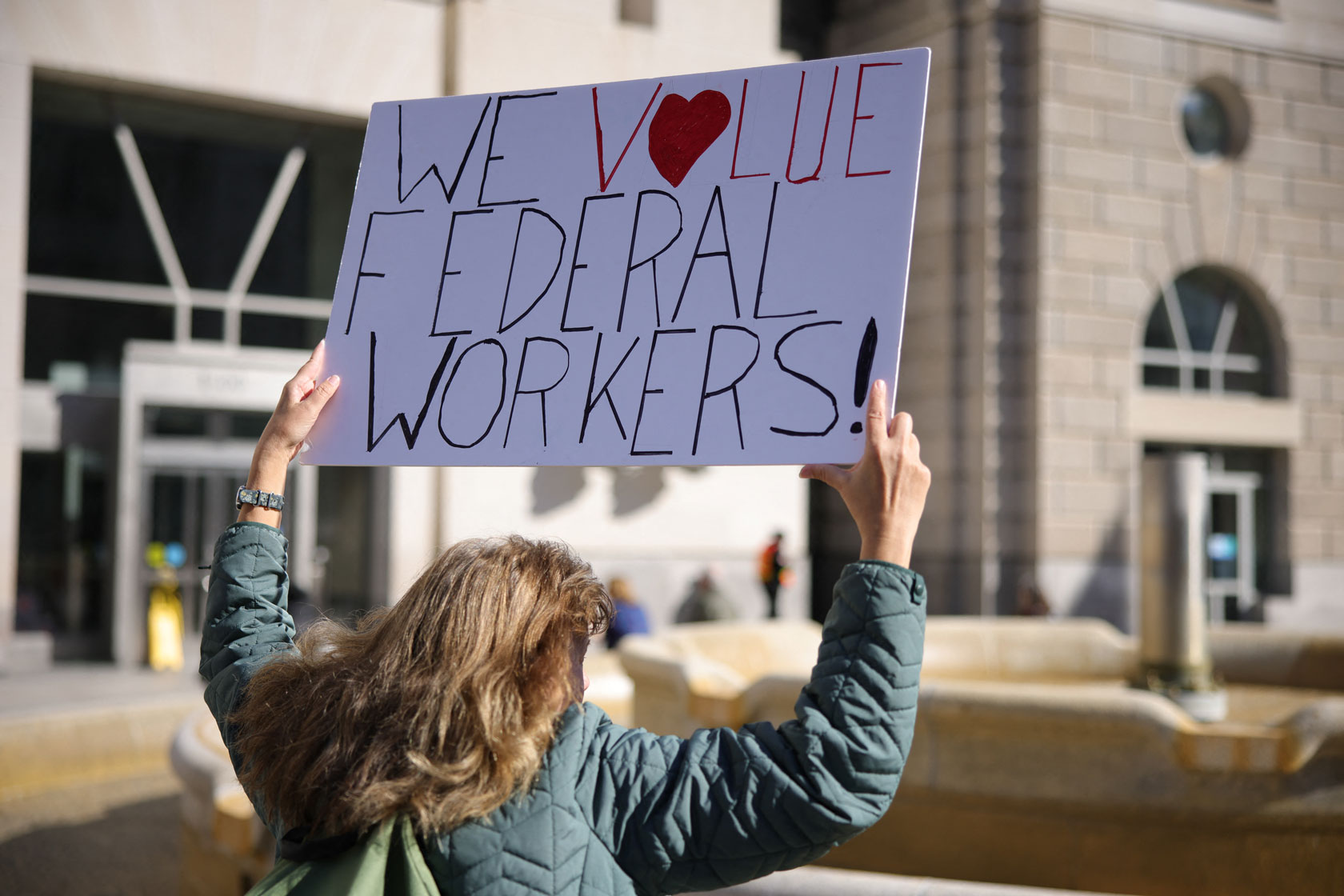 A person holds a sign outside of the USAID office.