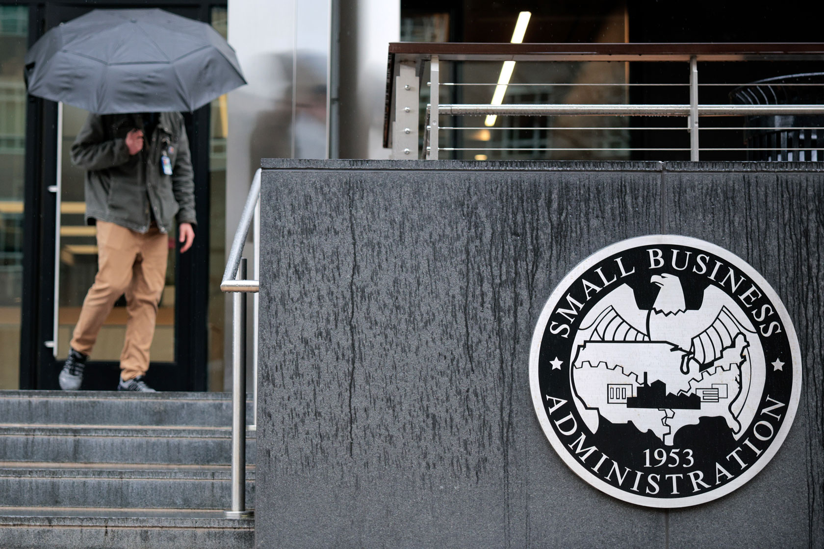 A person is seen holding an umbrella as they leave an office building.
