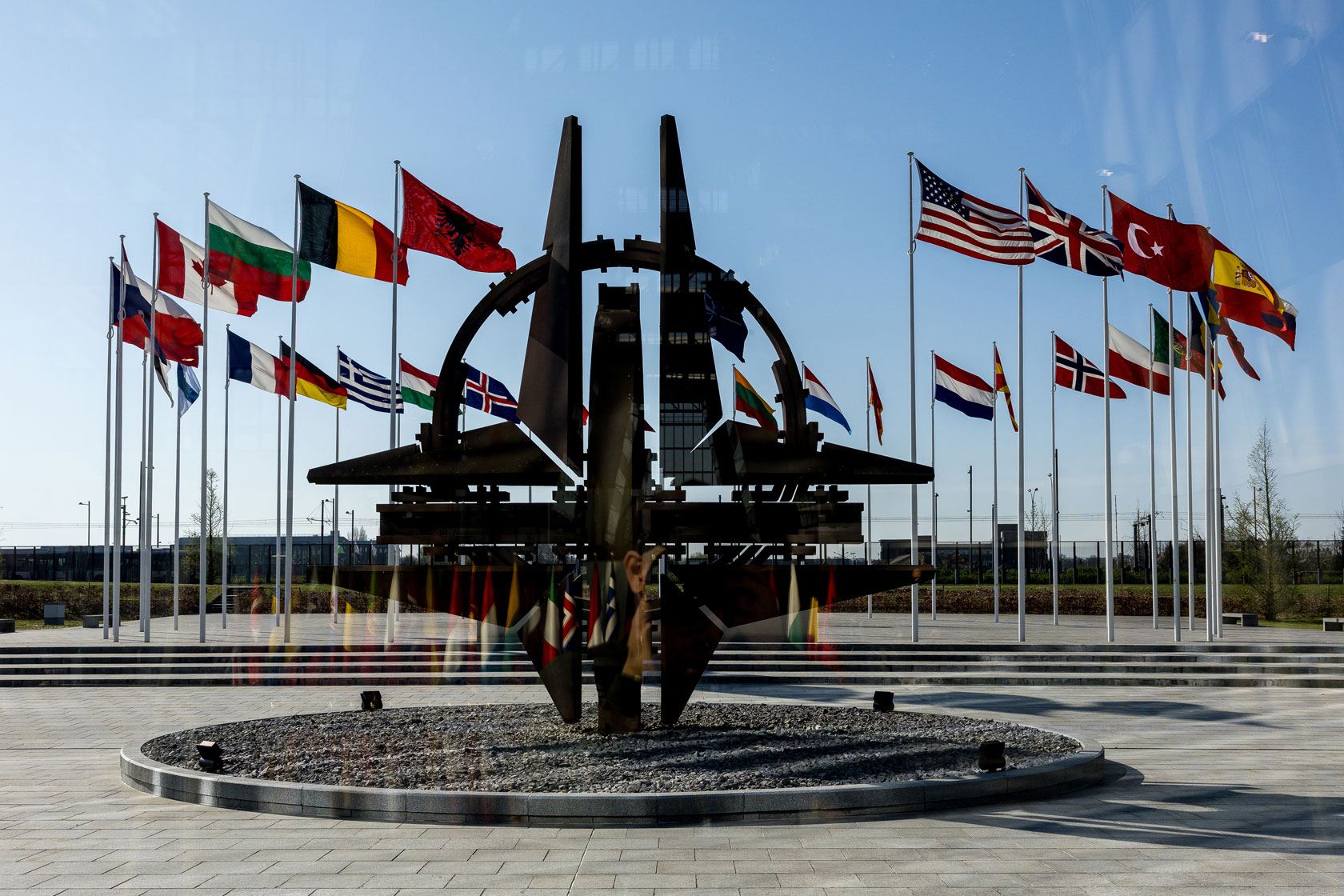The NATO star is seen surrounded by flags of the member nations.