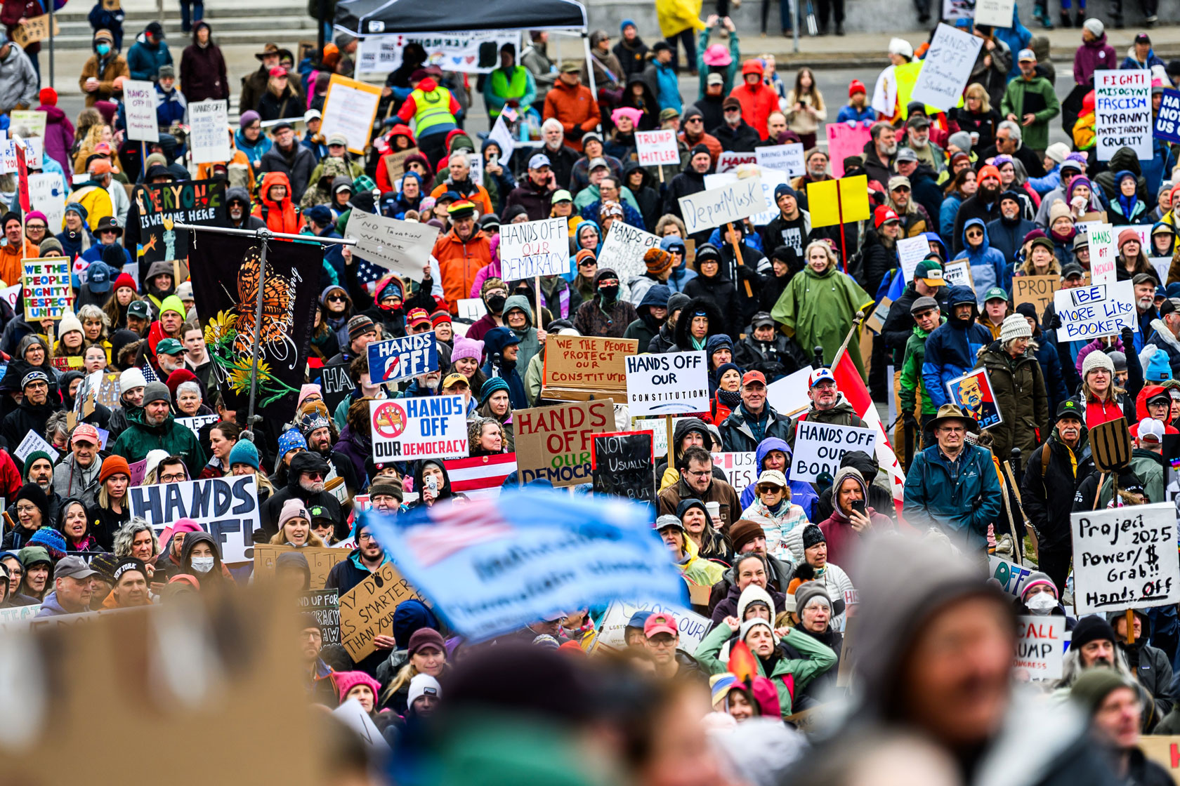 A crowd of protestors is gathered holding signs.