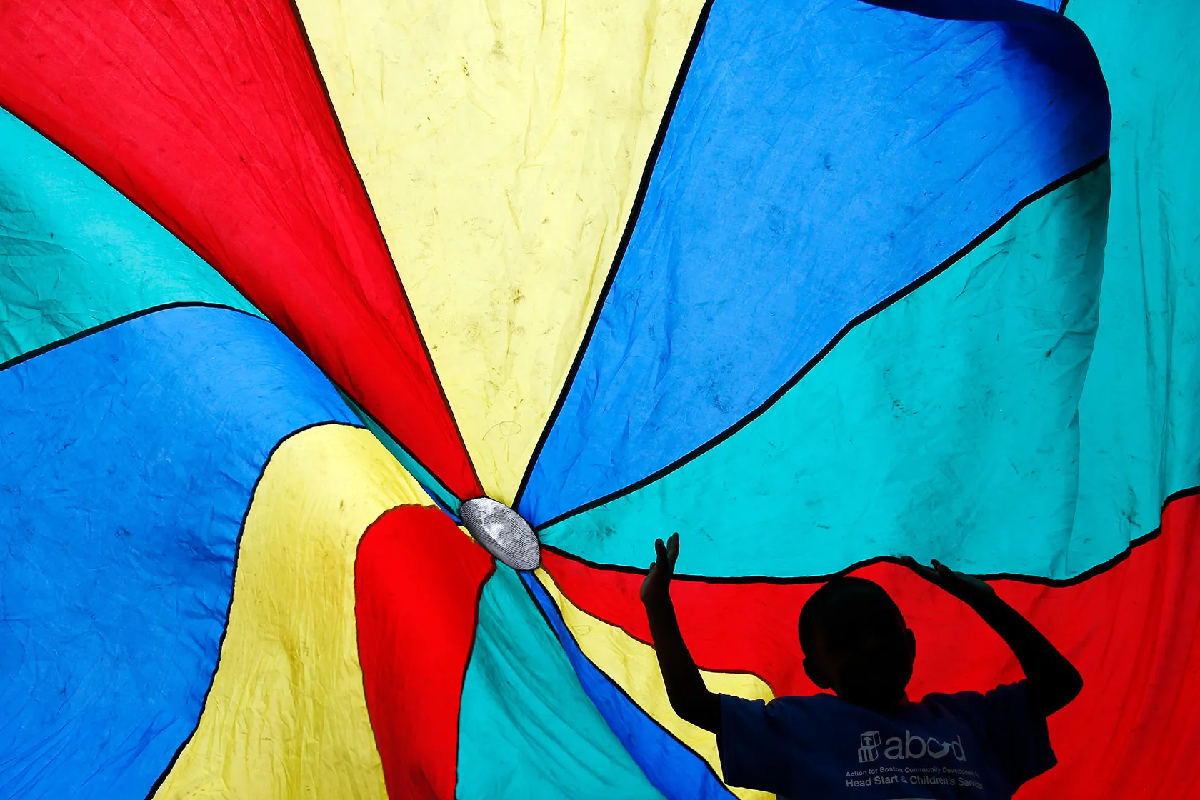 A child from the Hyde Park Head Start program plays under a parachute.