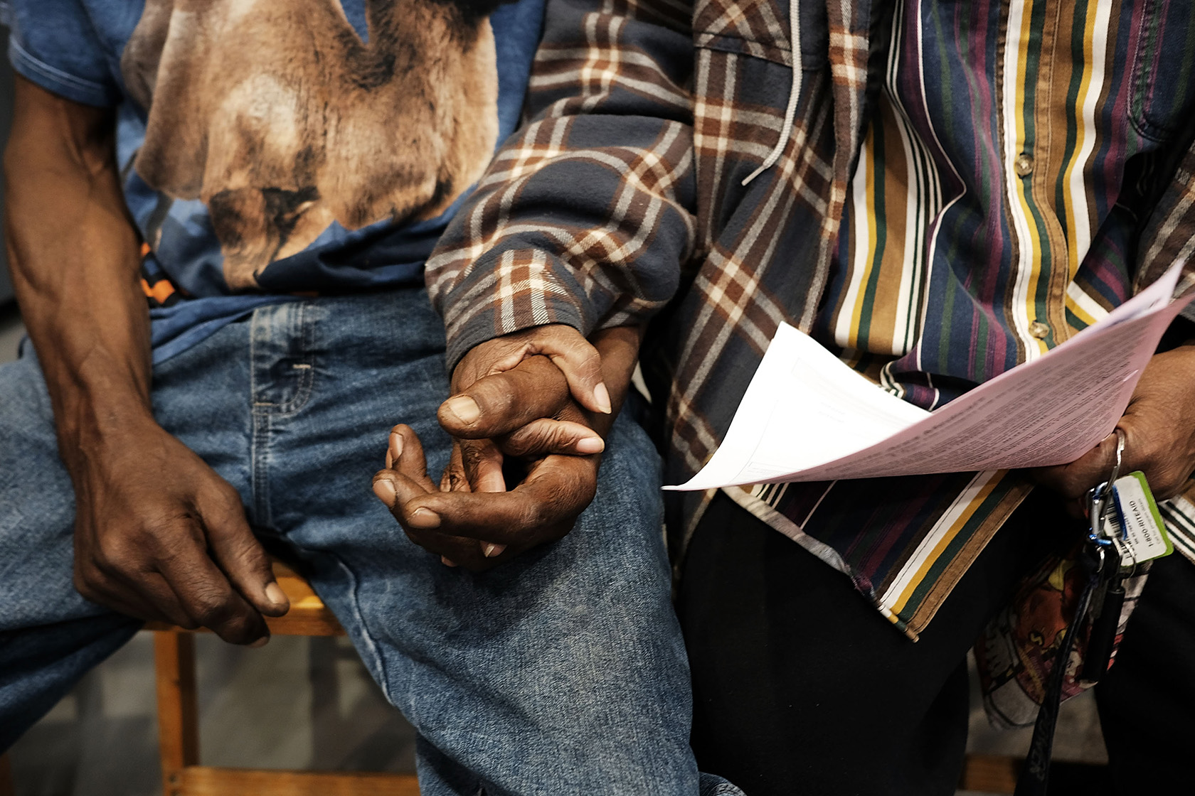 A couple hold hands as they fill out paperwork and wait to see a doctor.