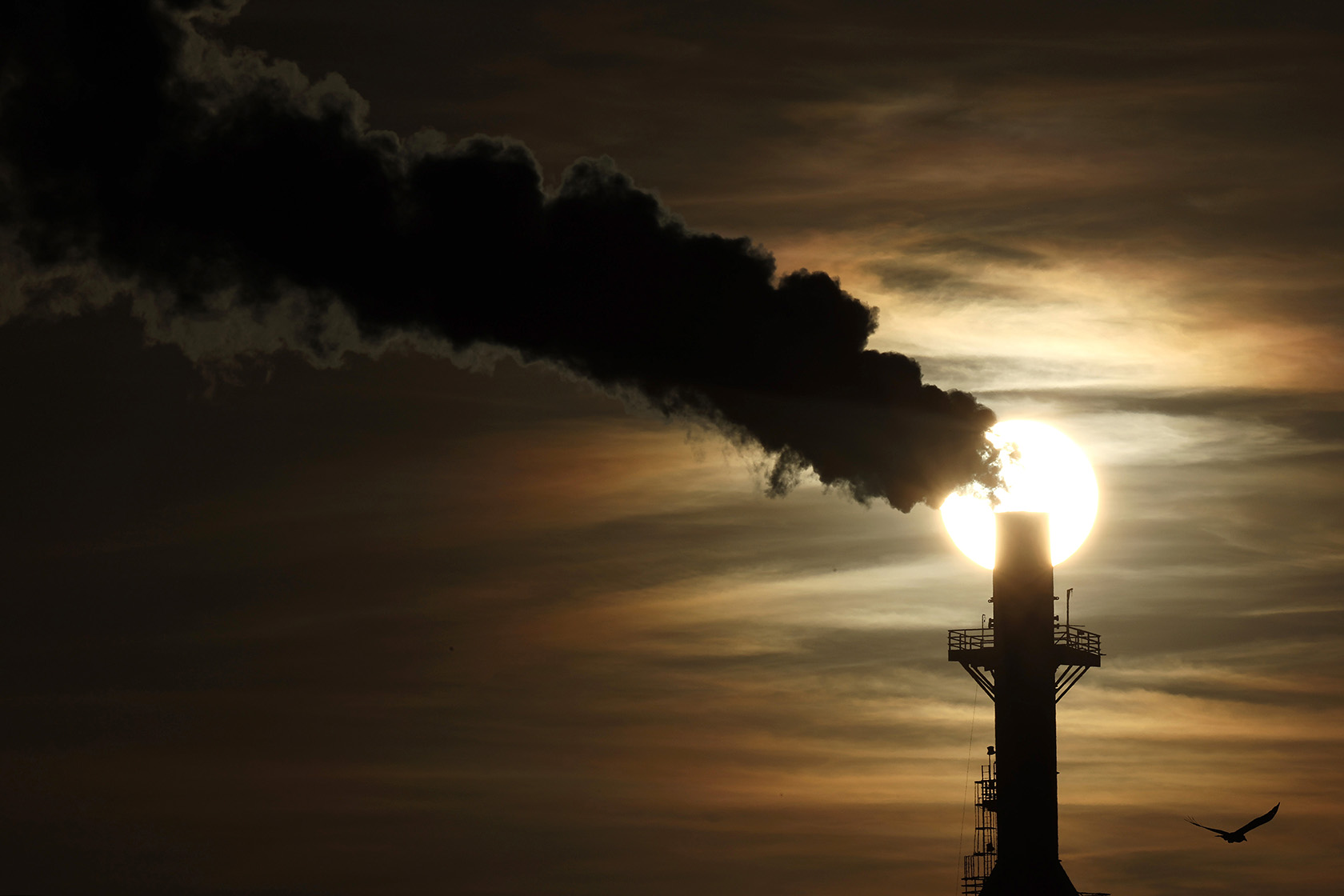 The sun sets behind an oil refinery in Wilmington, California.
