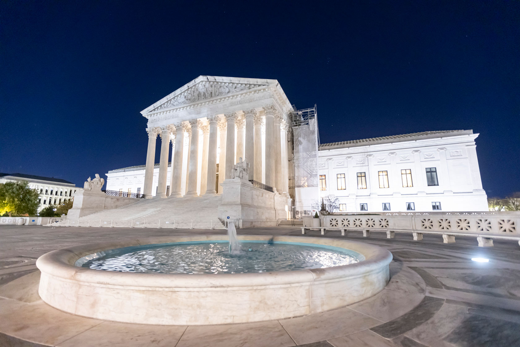 The U.S. Supreme Court building is illuminated at night.