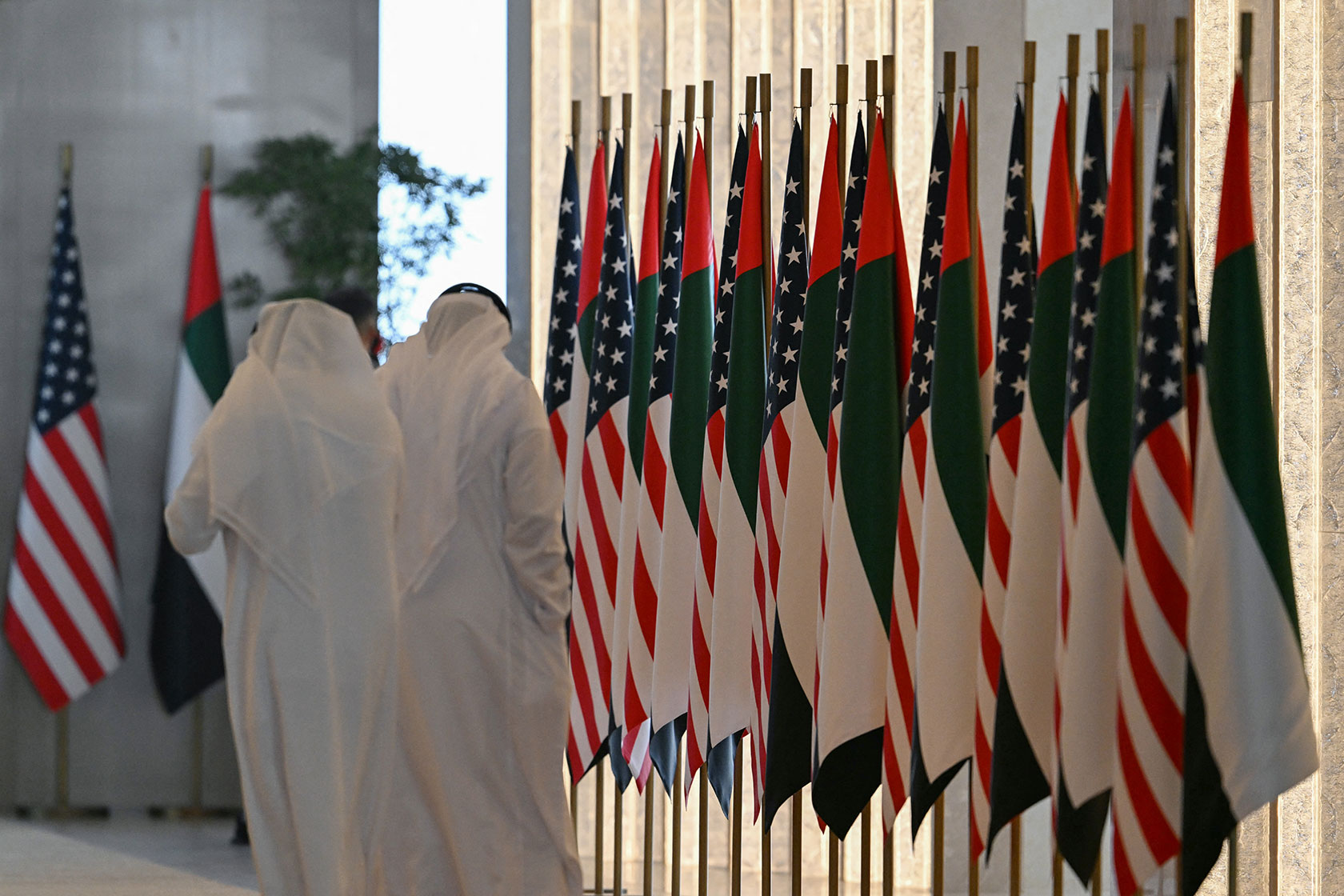 People walk past a line of U.S. and Emirati flags
