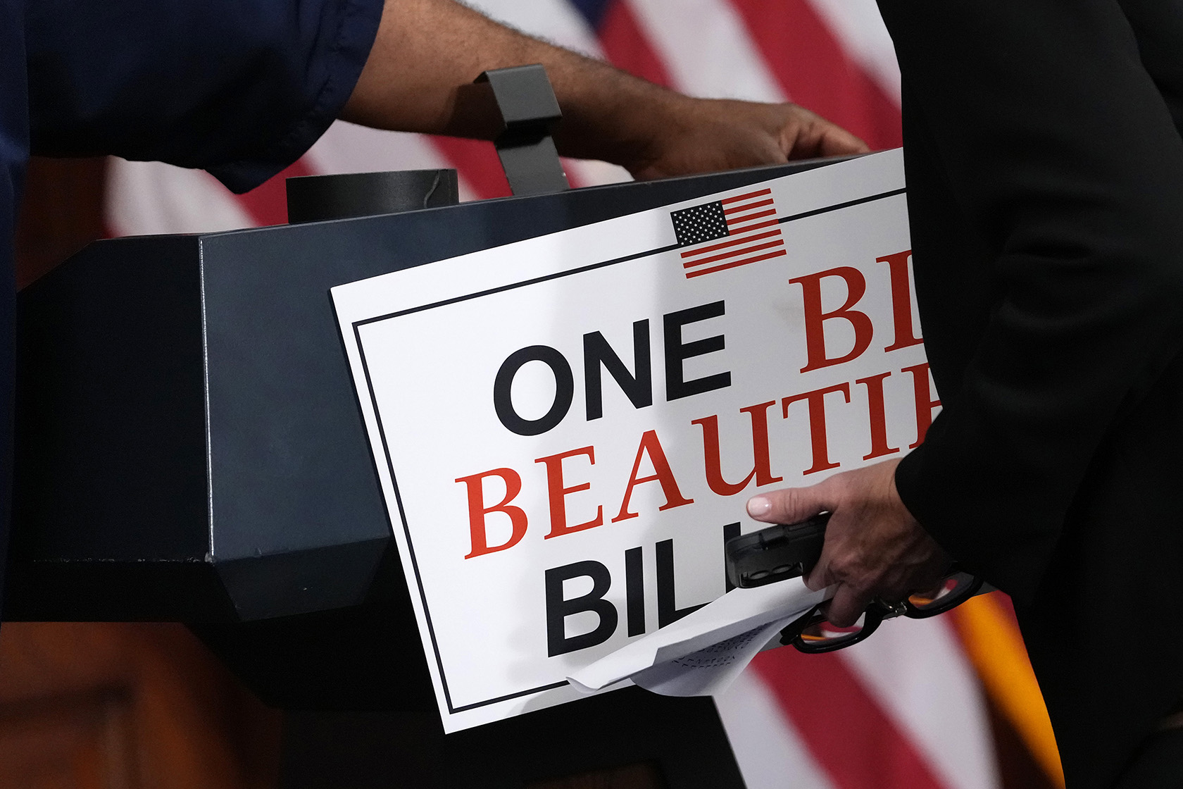 Staff members remove a sign following a press conference after House passage of the tax and spending bill.