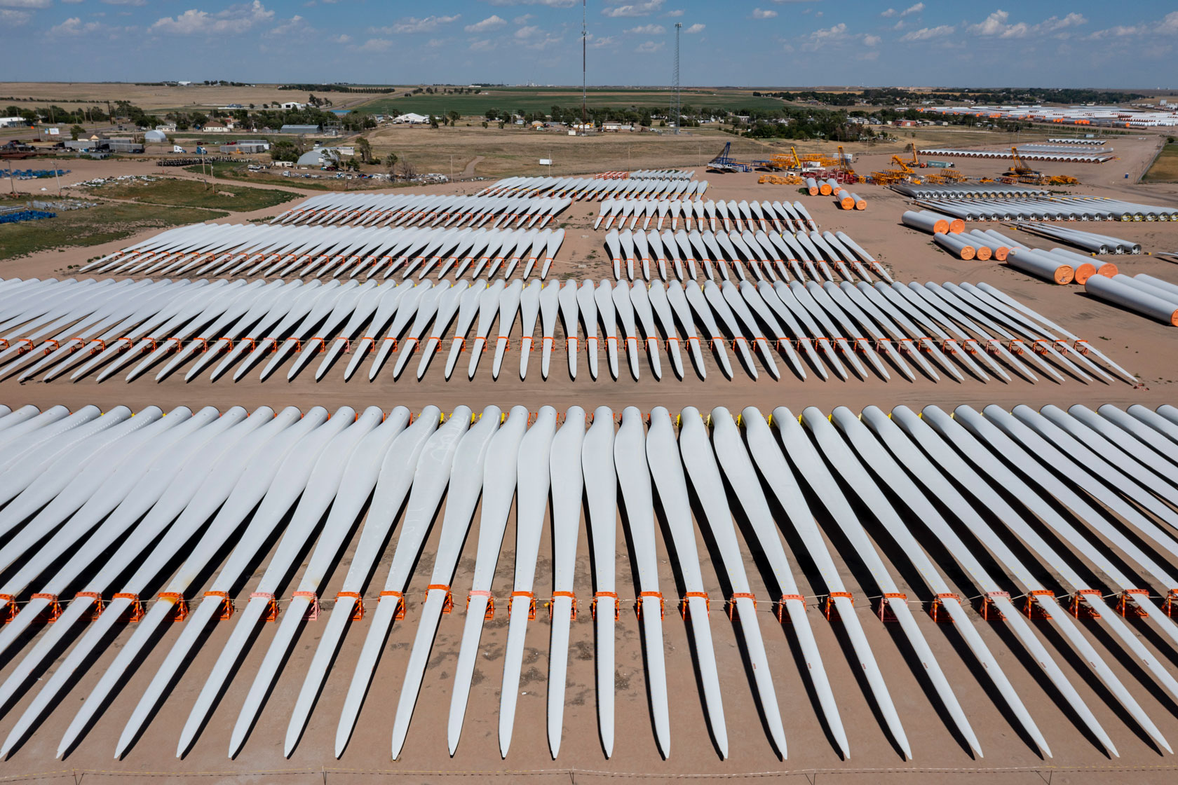 Rows of wind turbine blades stretch across an open field.