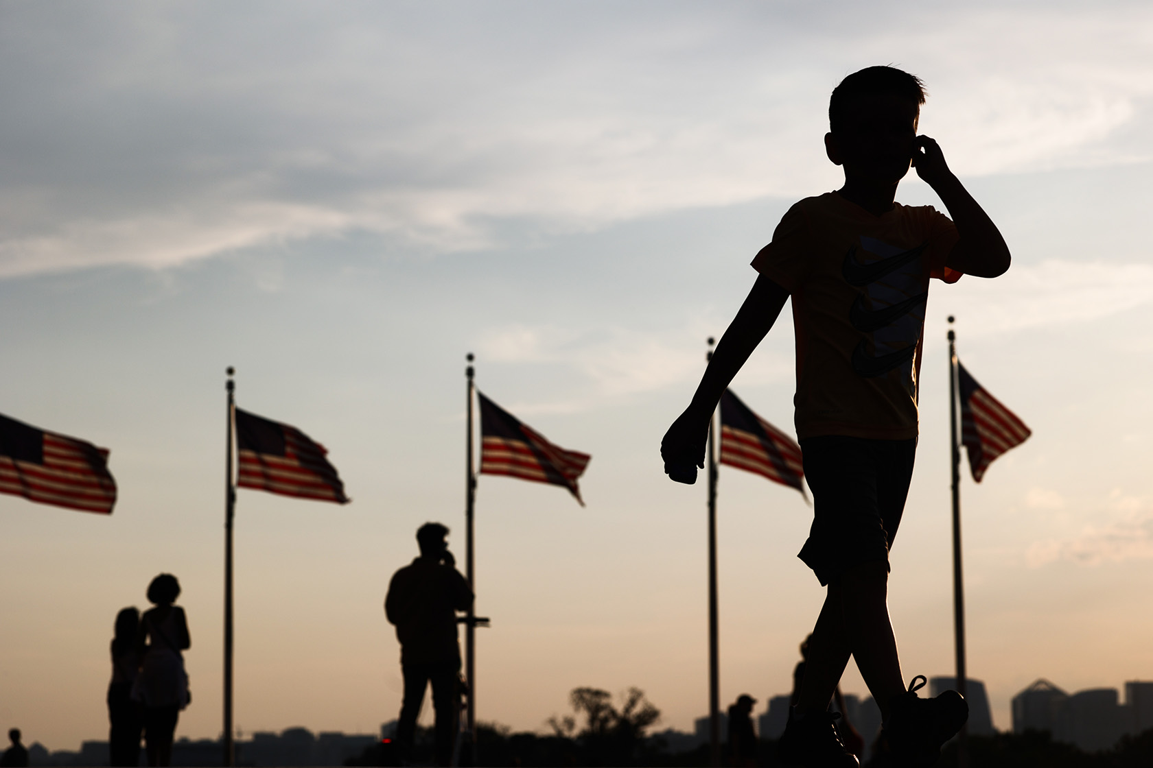 A child walks in front of American flags at the Washington Monument.