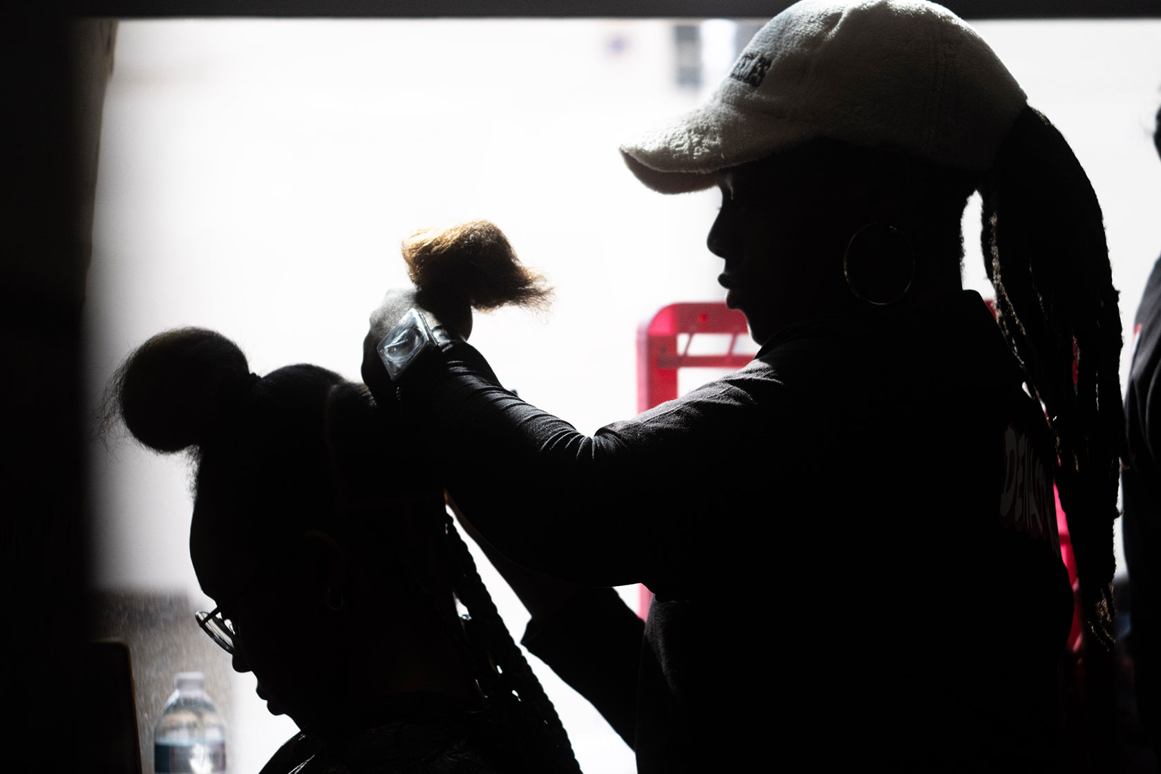 A hairstylist styling hair, seen in silhouette