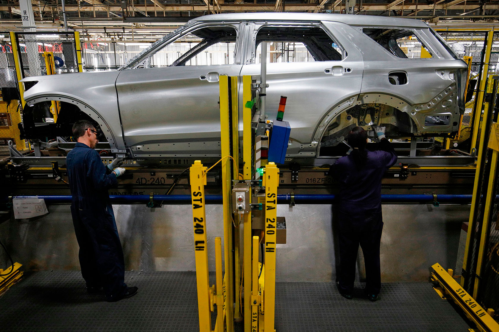 Two workers working on a raised car body