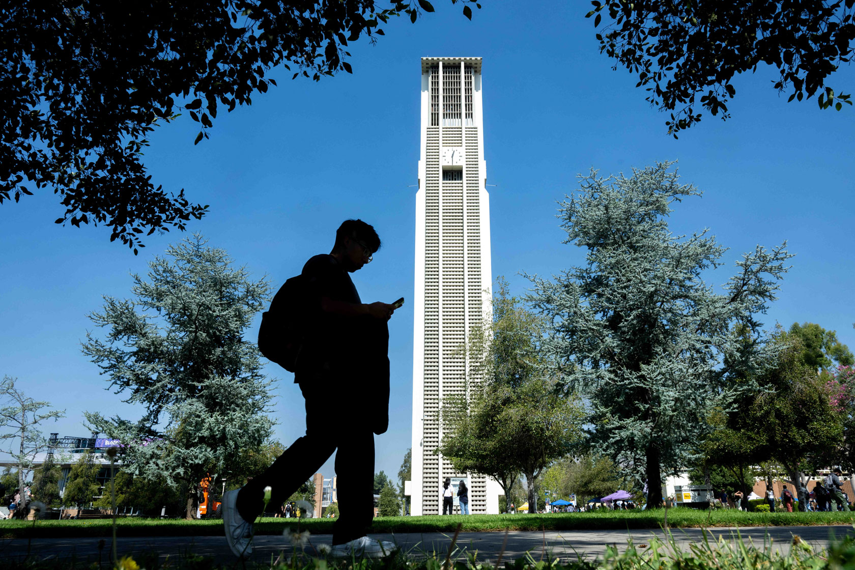 A student walks through the University of Riverside campus past the Carillon Bell Tower.