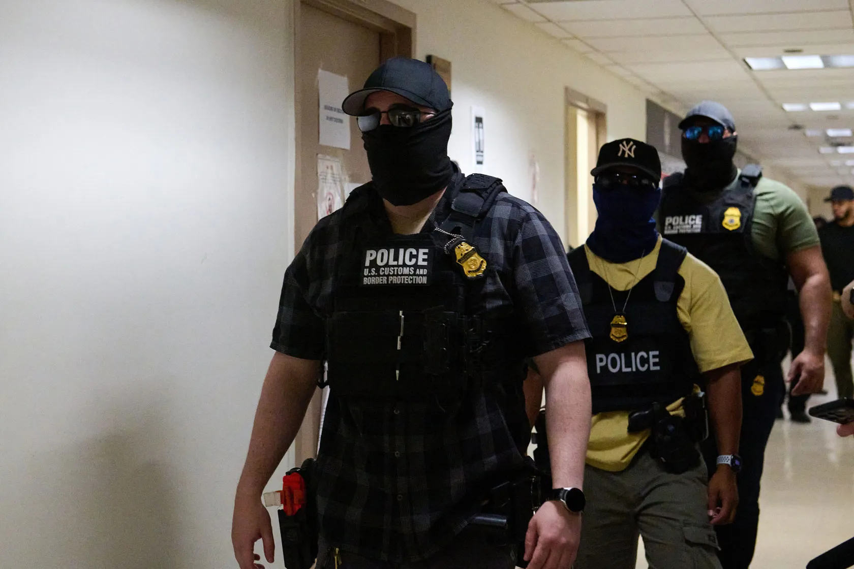 Masked federal agents working for U.S. Immigration and Customs Enforcement are seen walking down a hall in the Jacob K. Javits Federal Building in New York