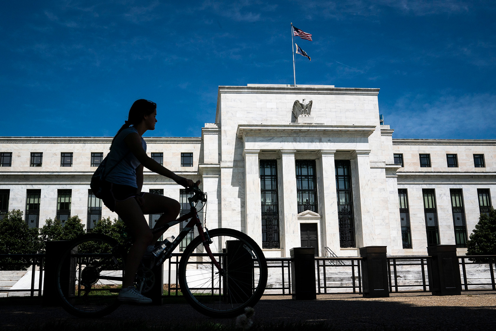 A cyclist passes the Marriner S. Eccles Federal Reserve Board Building.