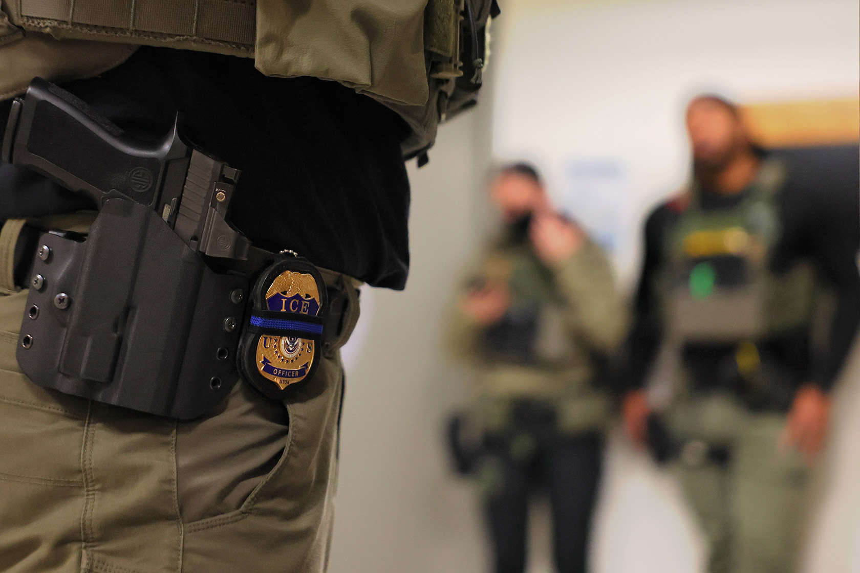 ICE officers patrol the halls of an immigration court building.