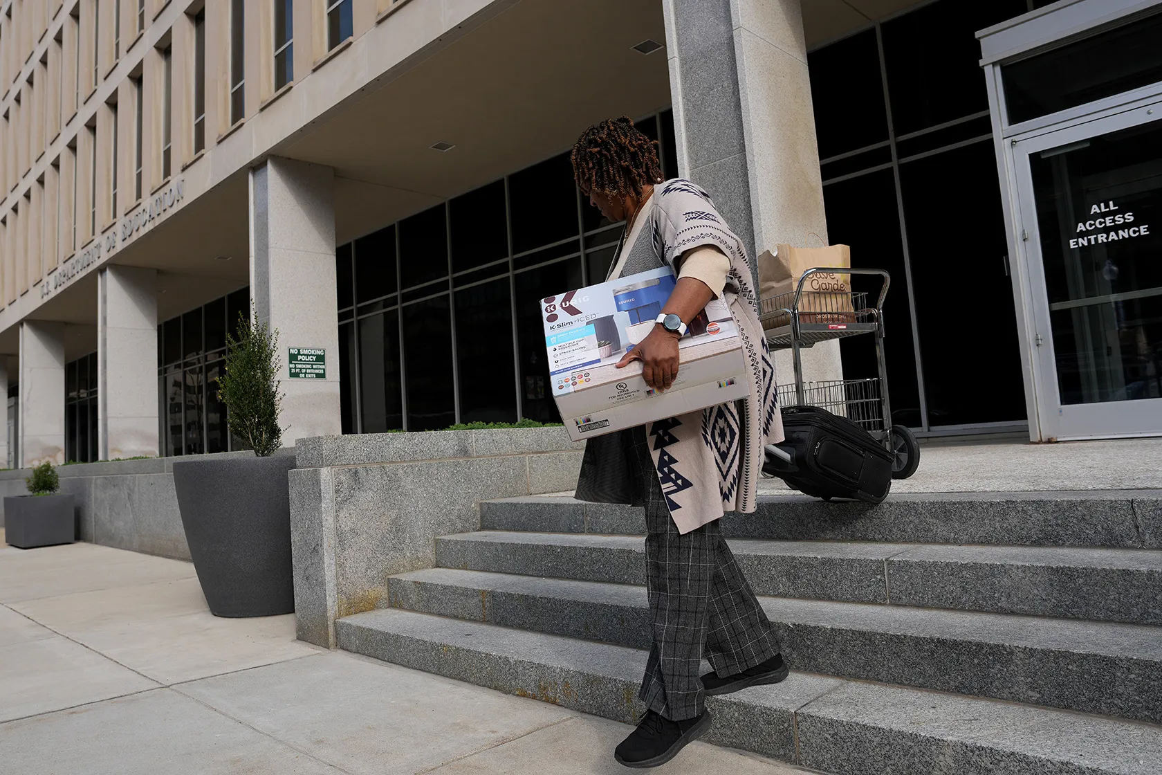 A U.S. Department of Education employee leaves the building with their belongings.