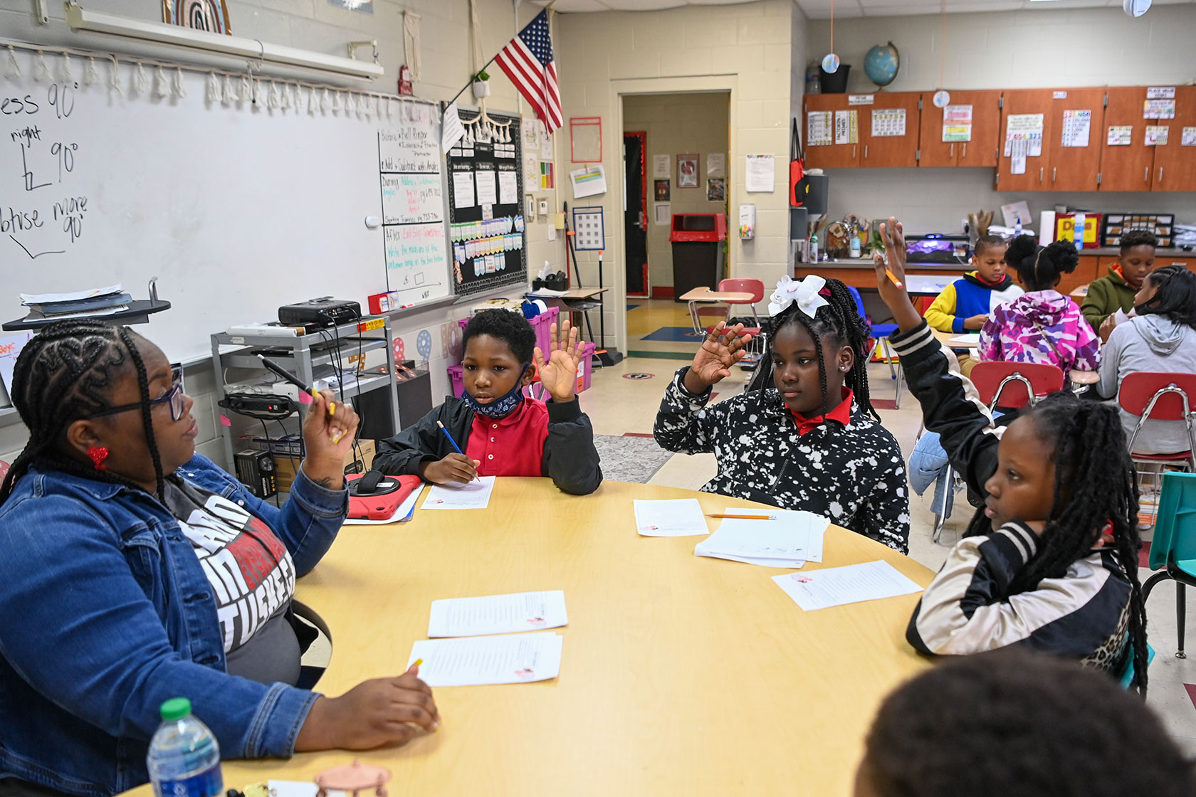 Teacher sitting at classroom table with students