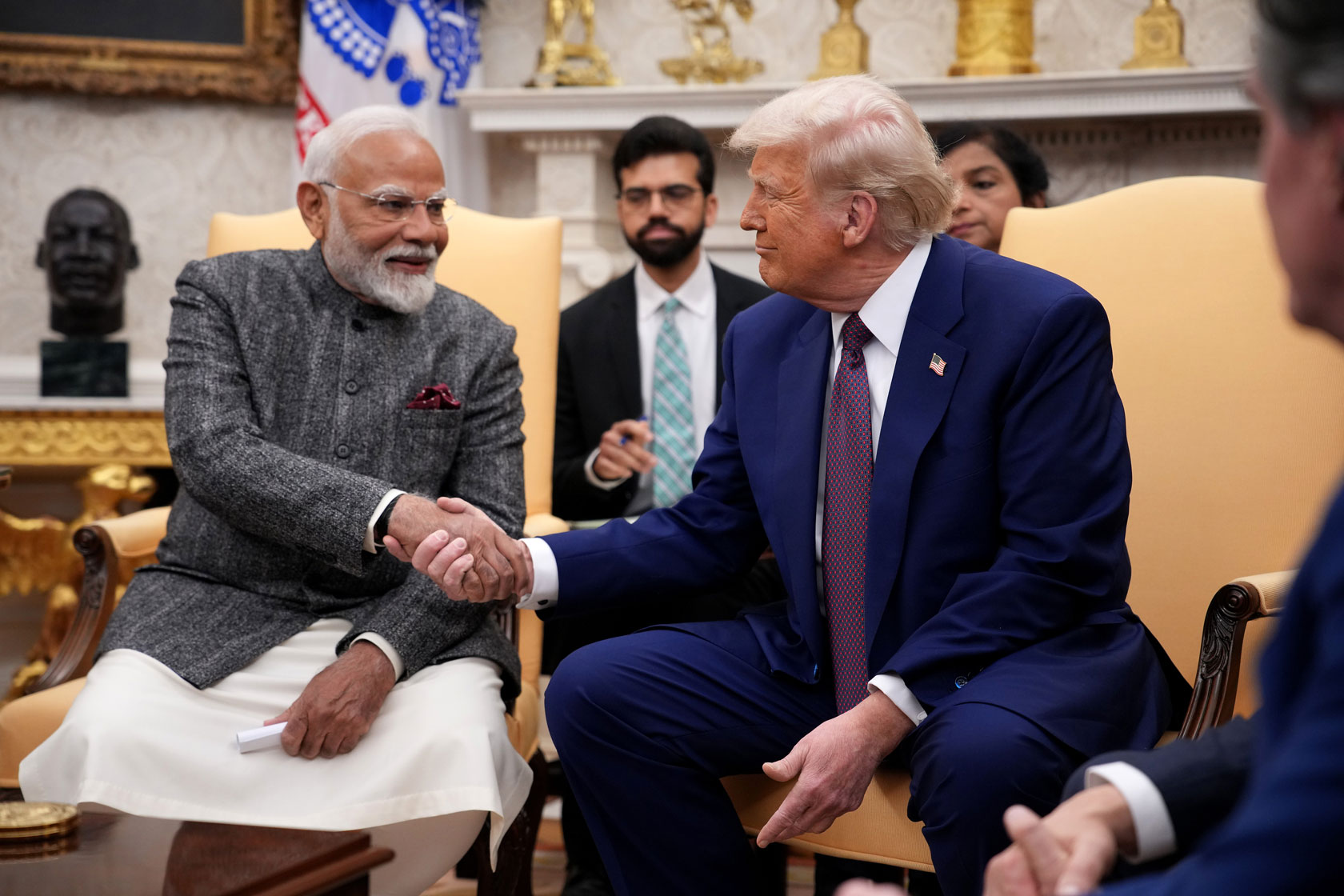 Prime Minister Narendra Modi of India and President Donald Trump, both seated, shake hands in the Oval Office at the White House.
