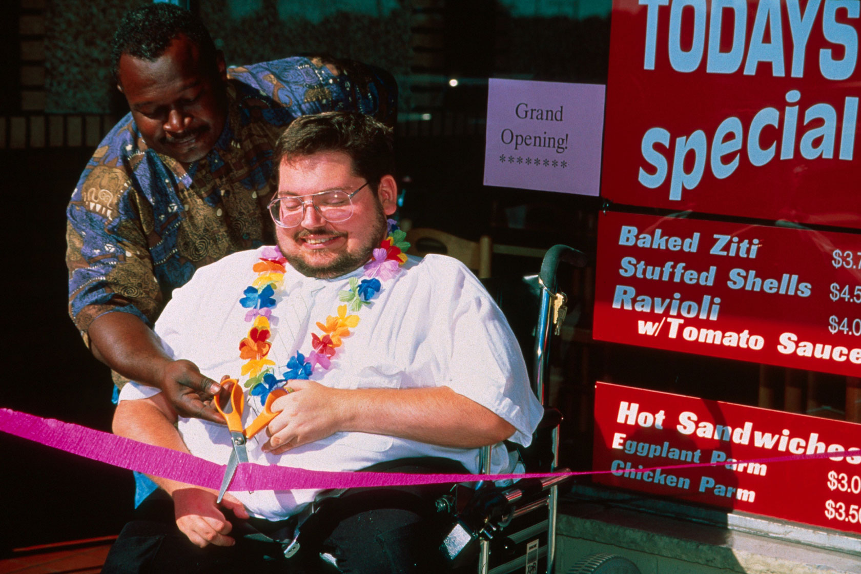 Two men, one of them in a wheelchair, celebrate the opening of a small business in New Jersey.