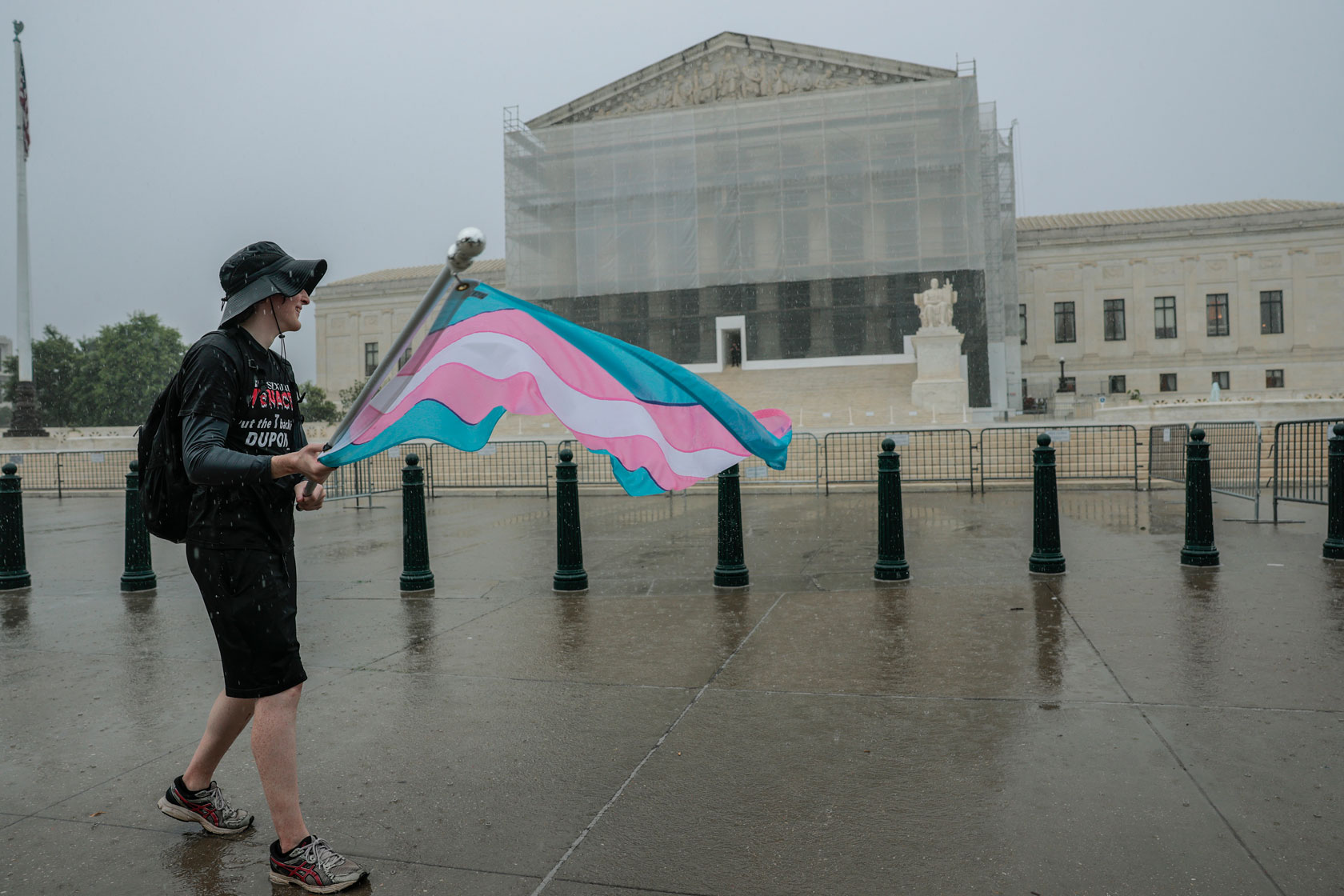 A protester holding a transgender pride flag walks past the U.S. Supreme Court building.