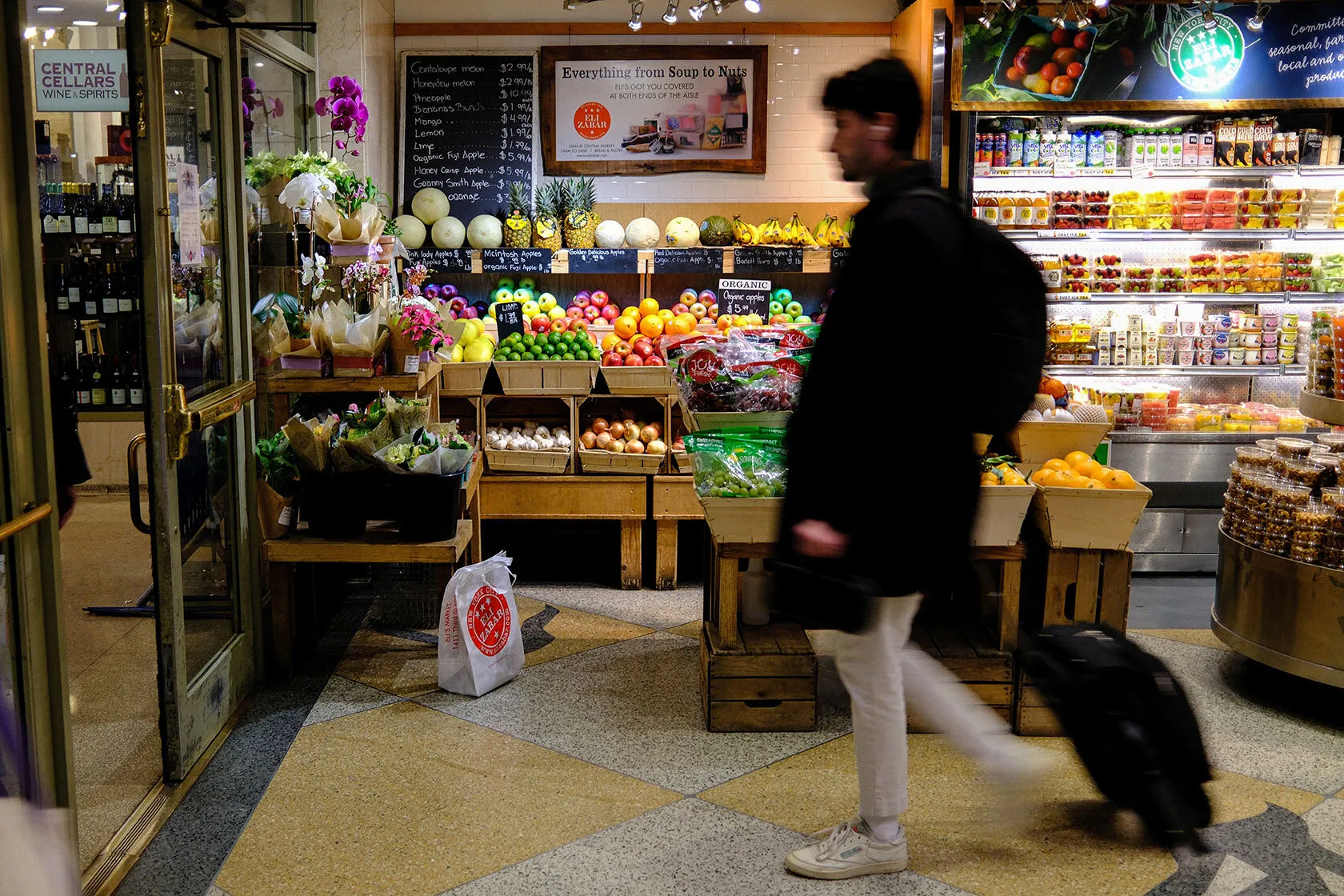A person walks past a grocery store display of fruits and vegetables