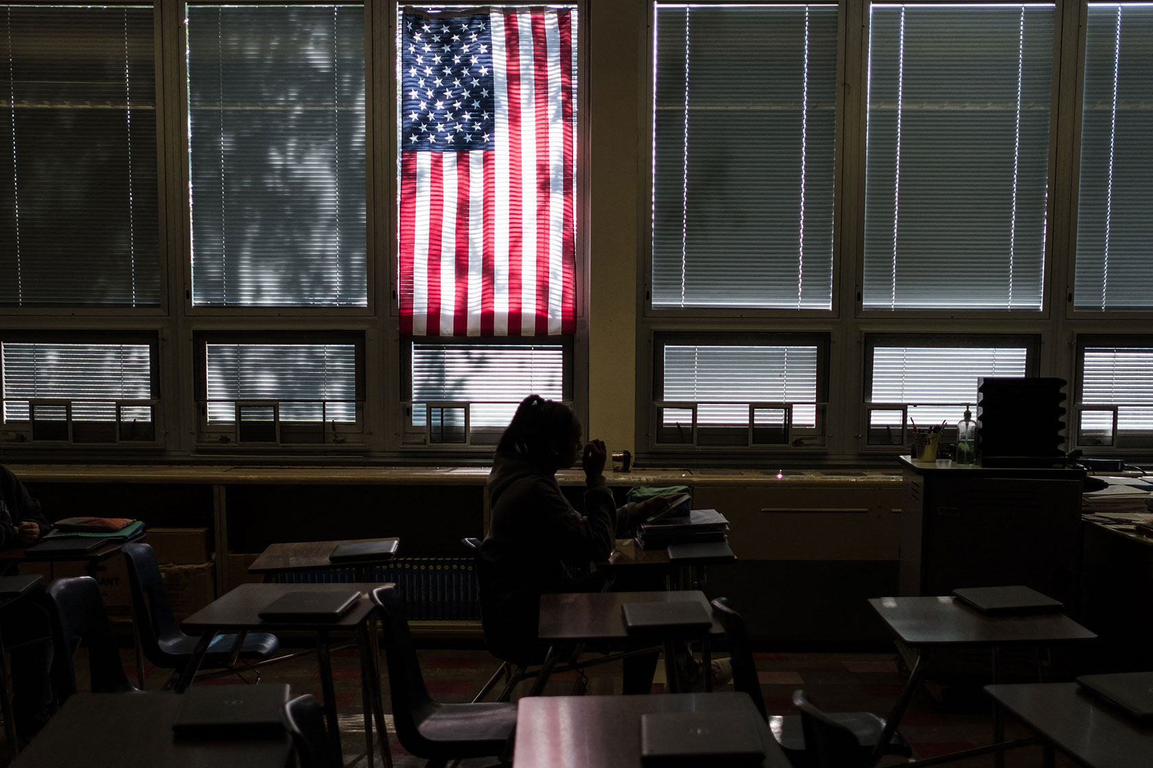 Silhouetted student in classroom beneath American flag