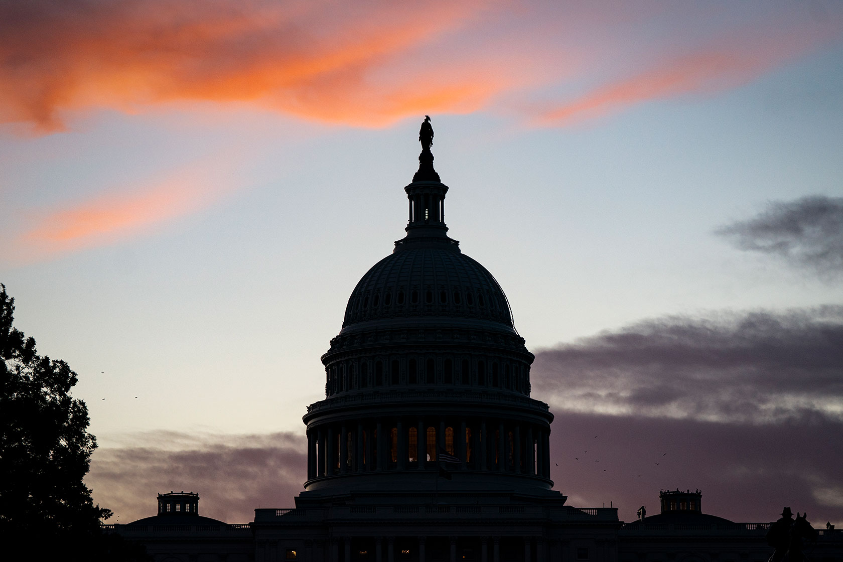 U.S. Capitol in shadow under orange clouds