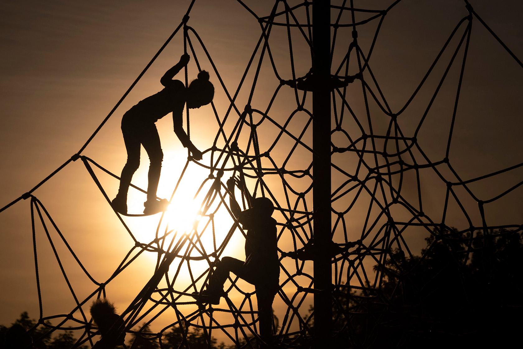 Children climb on play equipment during sunset in Liberty State Park.