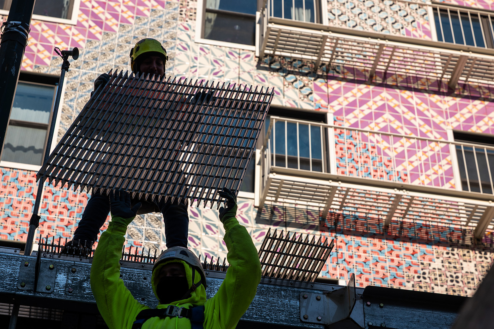 Construction workers handle a metal grate in New York.