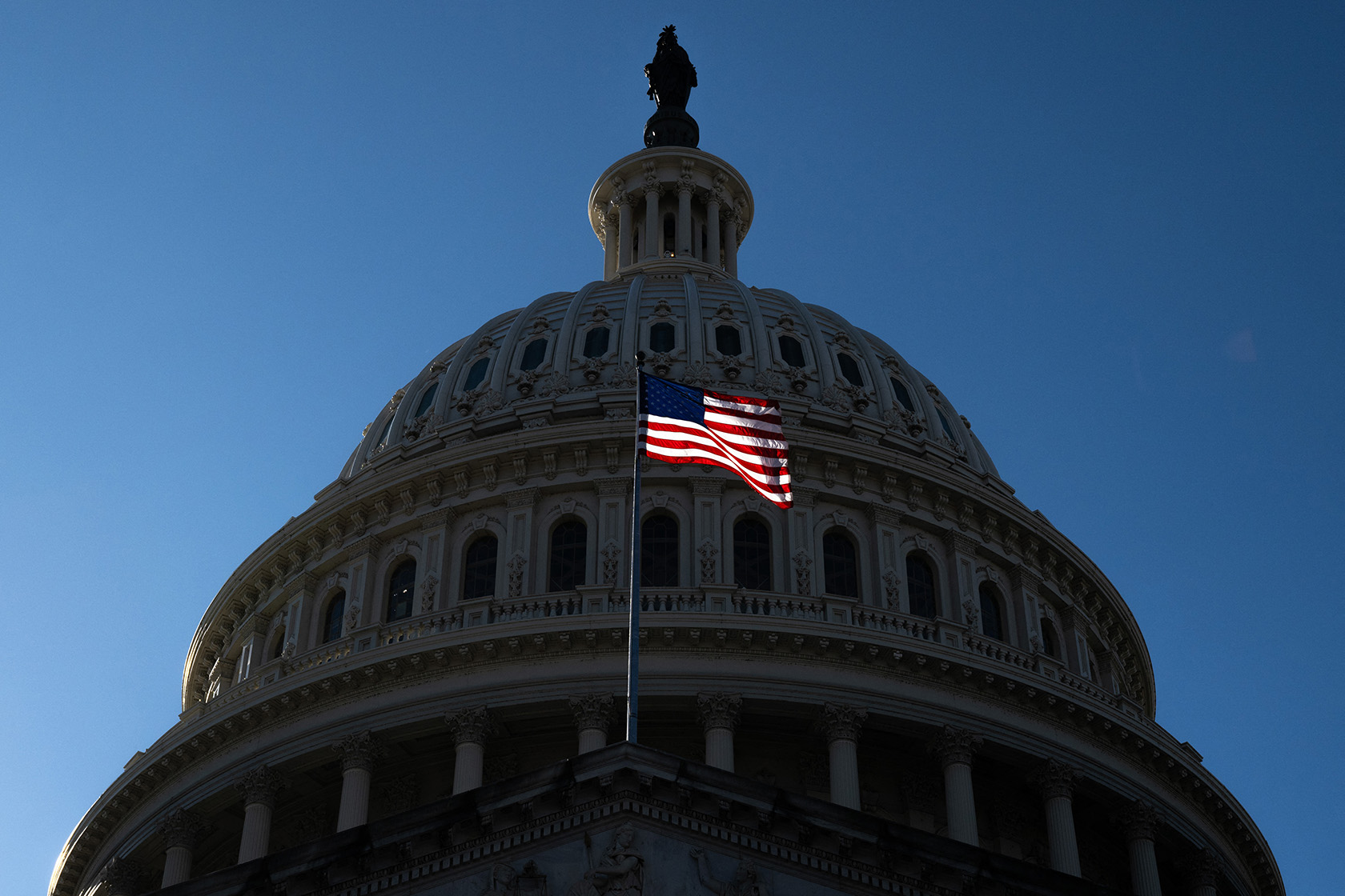 An American flag flies near the dome of the U.S. Capitol.