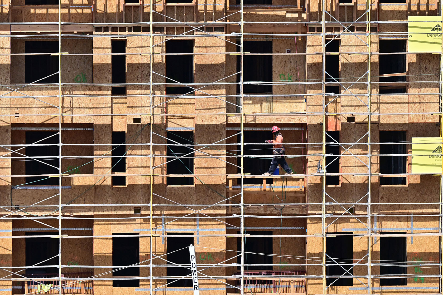 A construction worker on scaffolding in front of building infrastructure