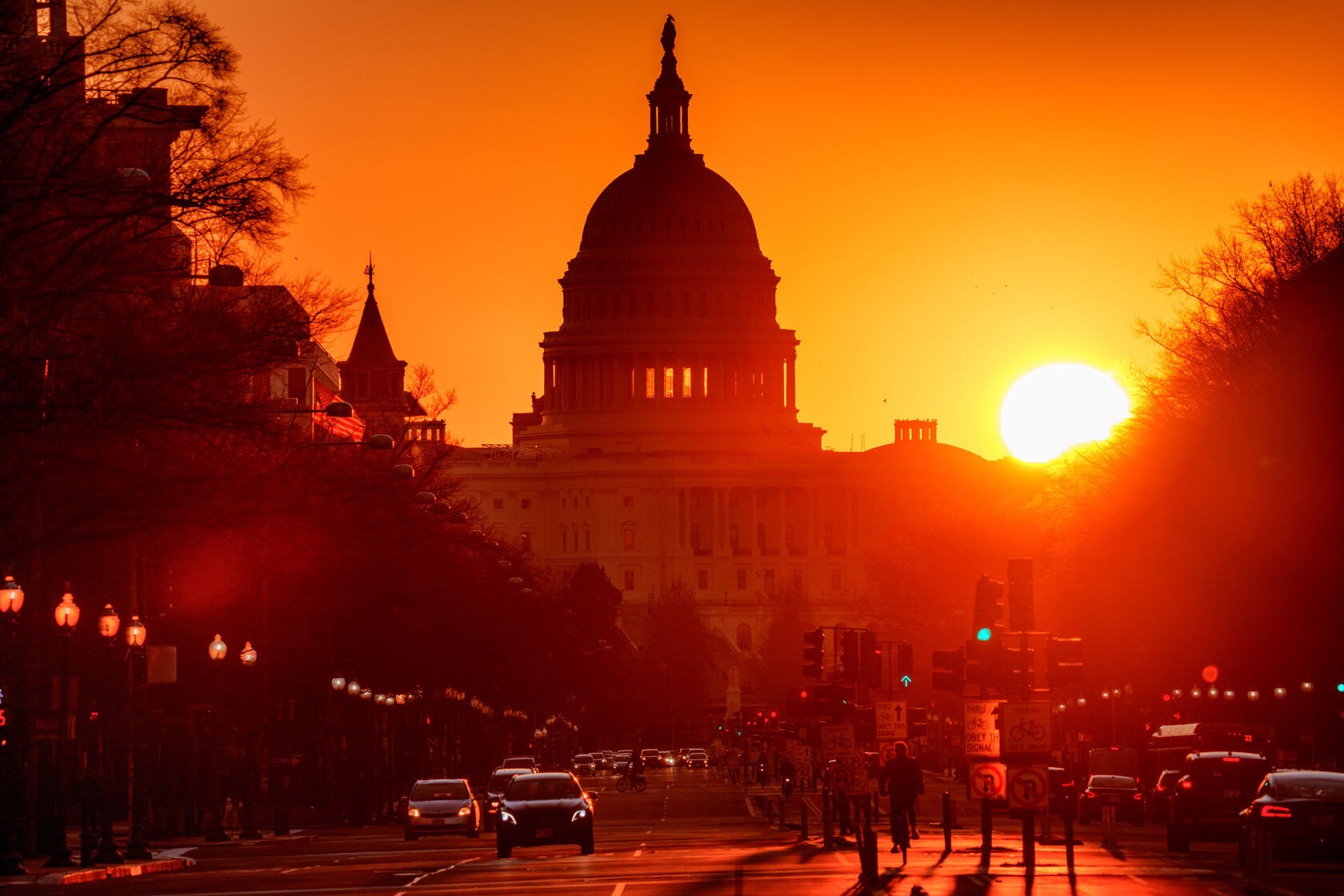 Traffic moves along Pennsylvania Avenue as the sun rises behind the U.S. Capitol.