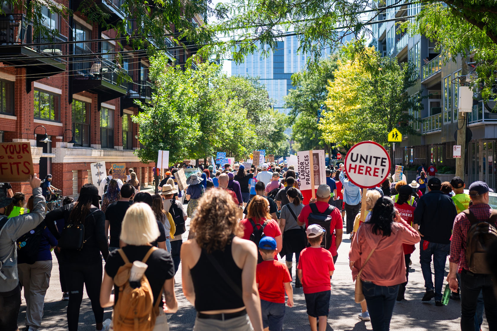 A group of people are seen marching holding signs on Labor Day.