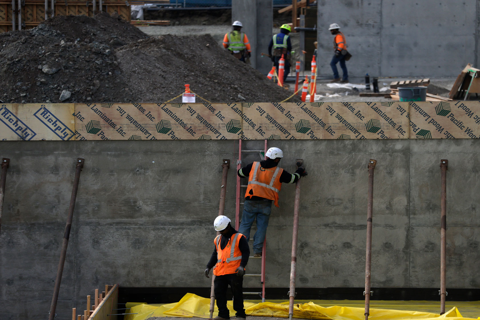 A construction worker on a ladder is one of five on the site of a new building in San Francisco.