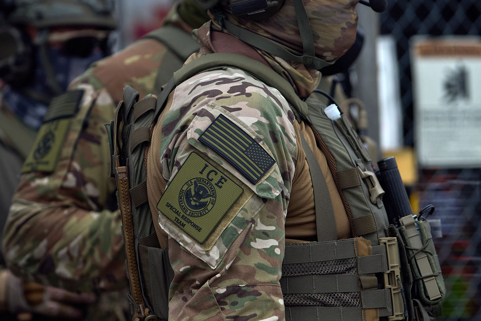 Arm and shoulder of federal agent with ICE DHS patch logo on camouflage uniform
