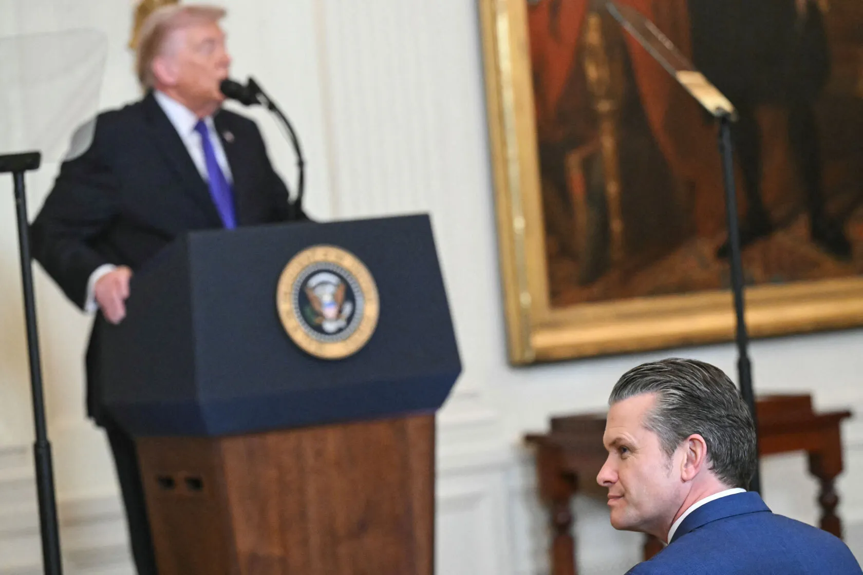 Secretary of Defense Pete Hegseth looks on as President Donald Trump speaks.