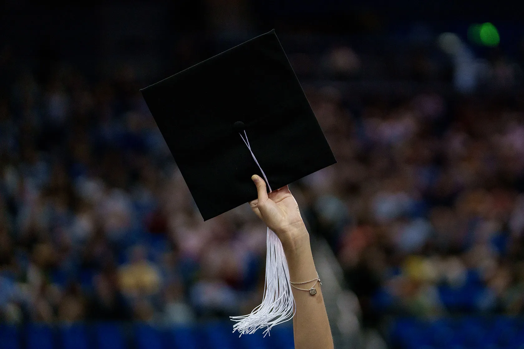 A hand raising a graduation cap