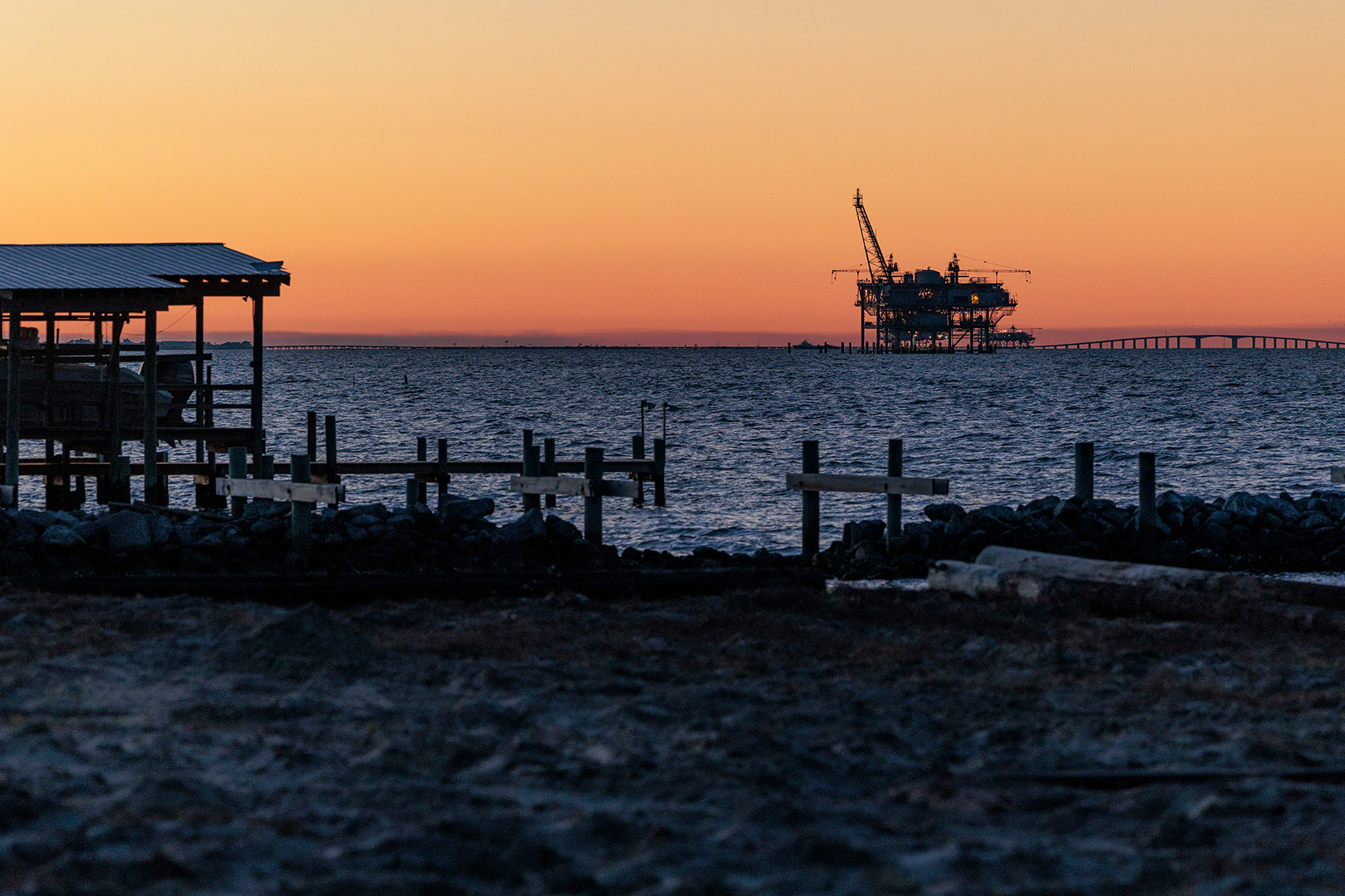 The sun sets behind an offshore drilling rig in the Gulf of Mexico.